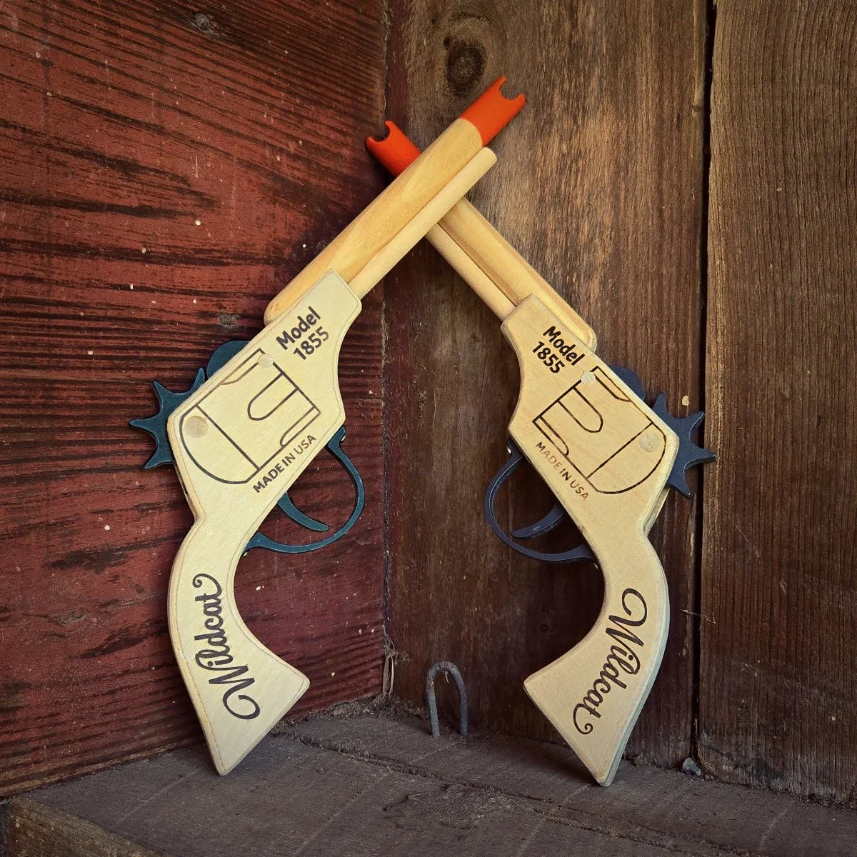 two rubberband toy revolver pistols leaning on rustic barn boards
