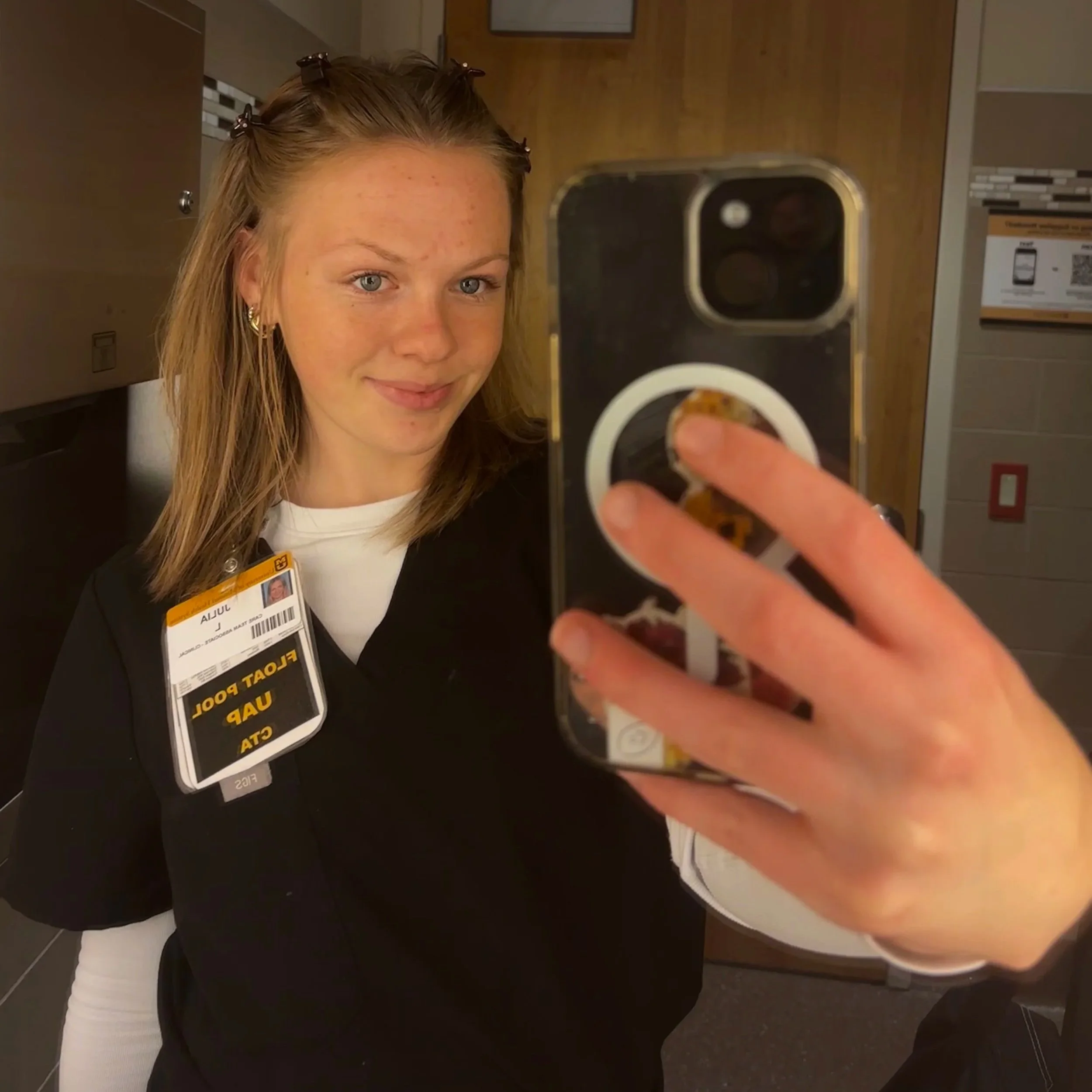 Julia Lipp takes a selfie wearing her nursing uniform in front of a hospital mirror.