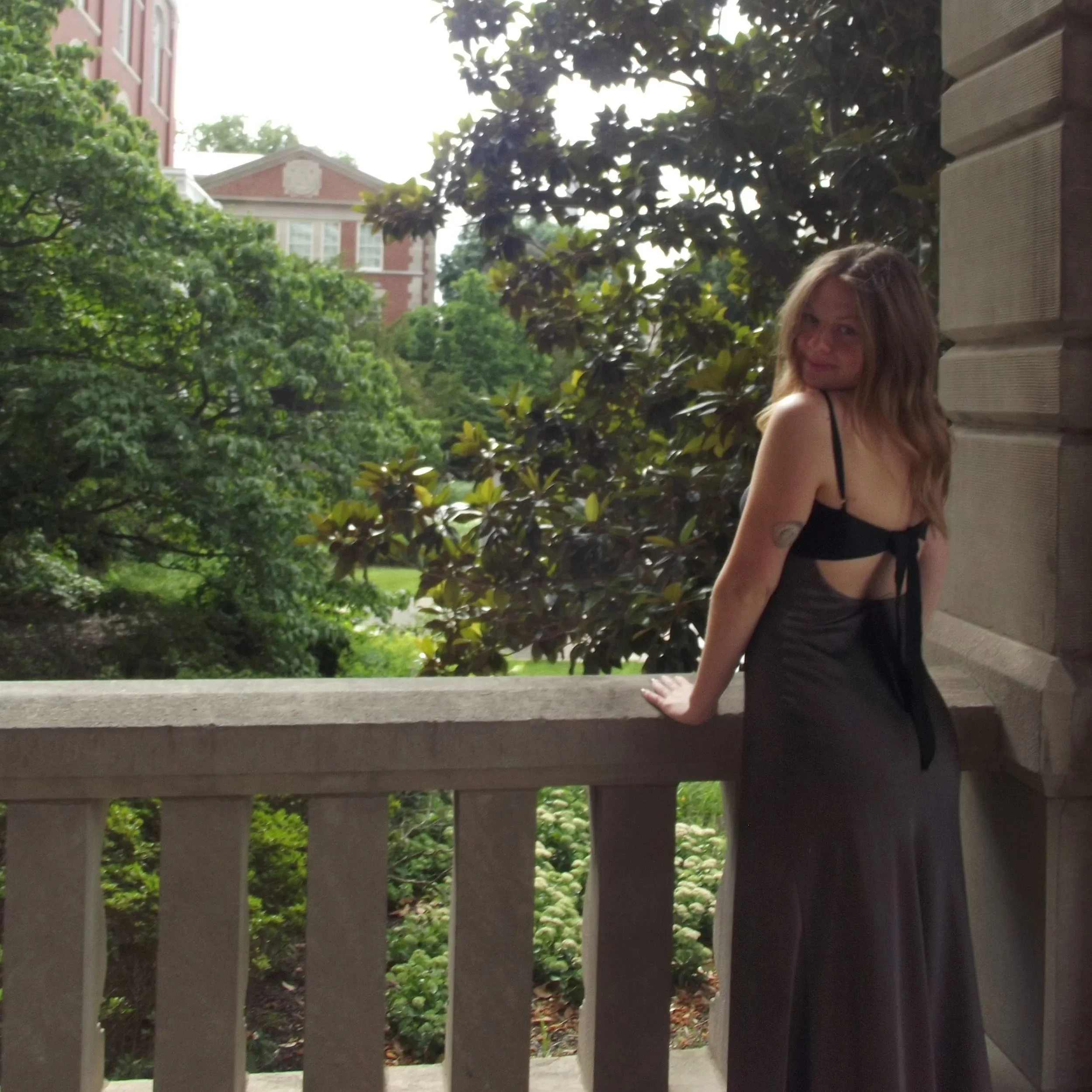 Julia Lipp standing on stone balcony wearing a black dress with a diabetic patch on her arm.