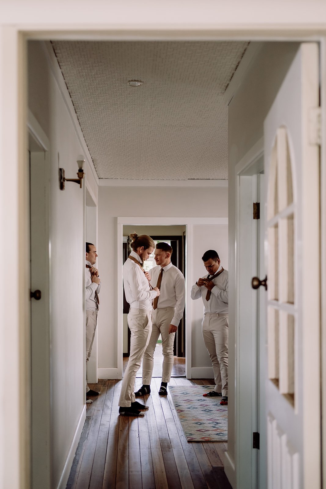 Groomsmen standing down hallway getting ready for ceremony