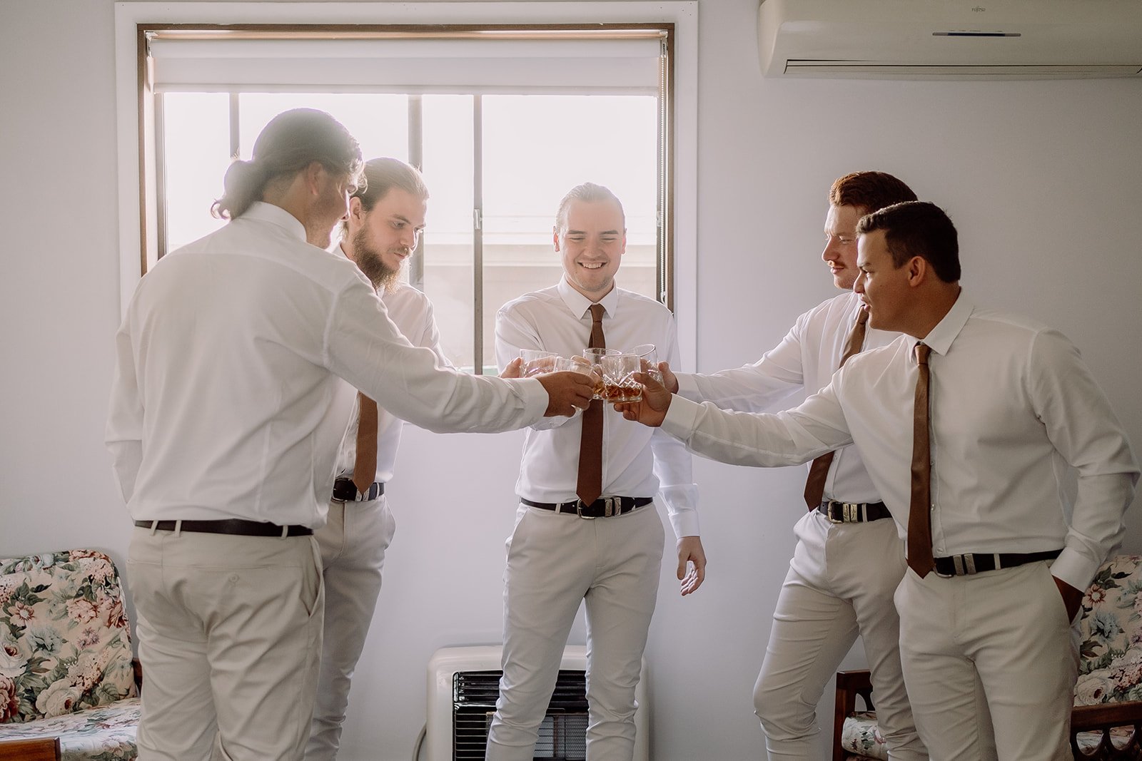 Groomsmen cheersing each other with scotch glasses