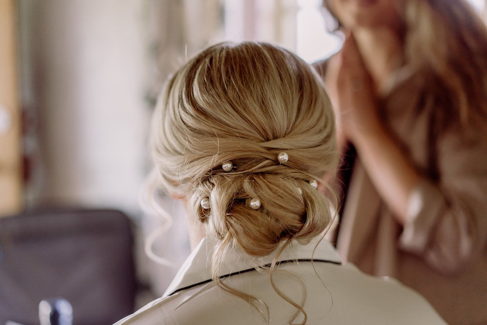 Bride's loose low bun wedding hair with white pearl hairpins