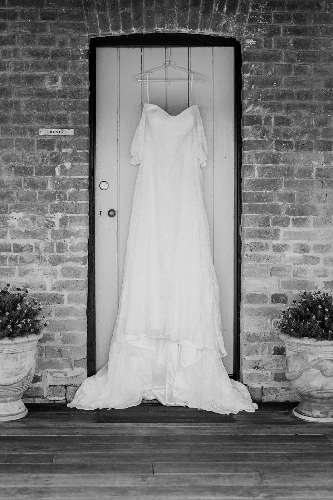 Bride's wedding gown with floral lace overlay, hanging on door at Tocal Homestead