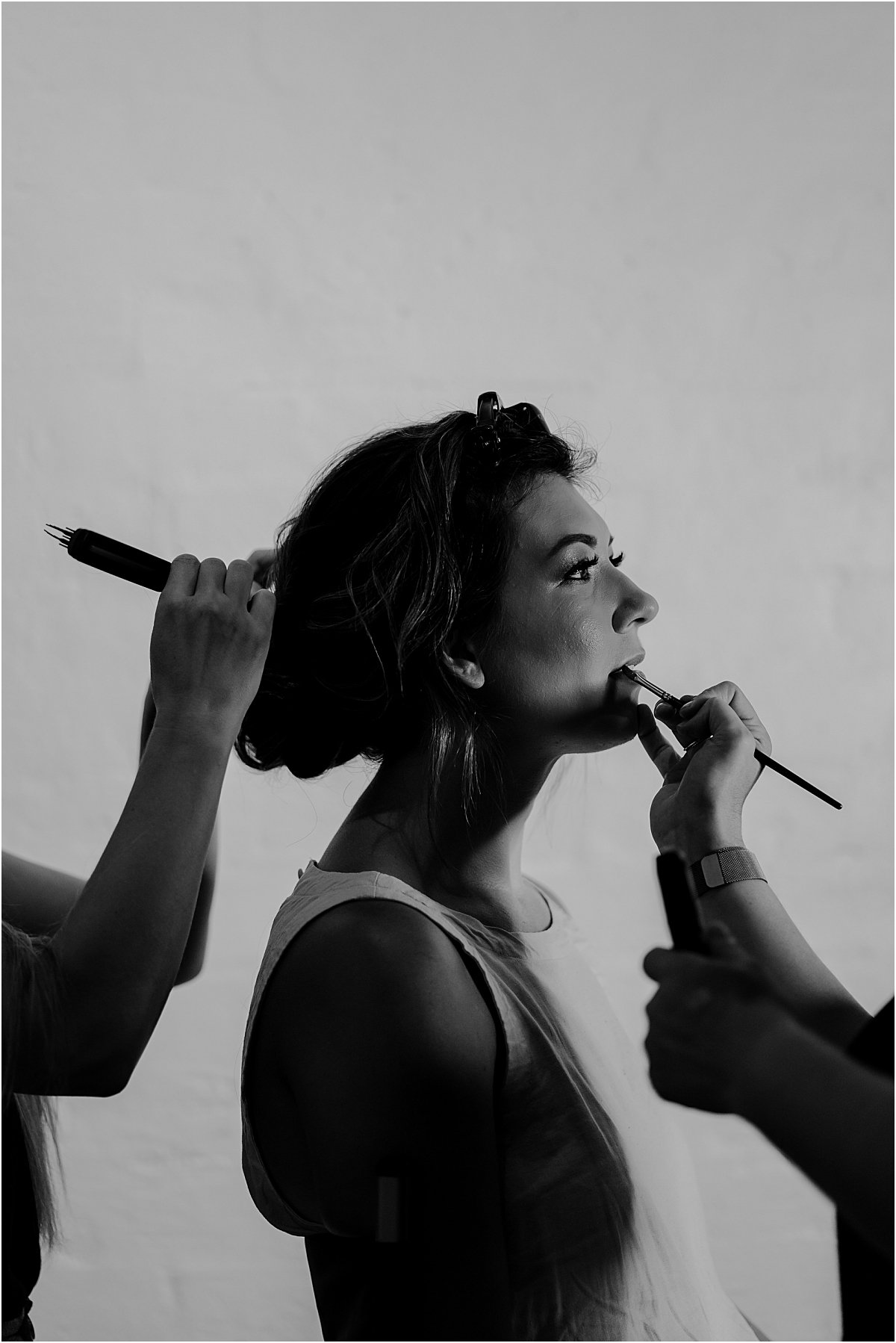Bride getting hair and makeup done at the same time, side profile image