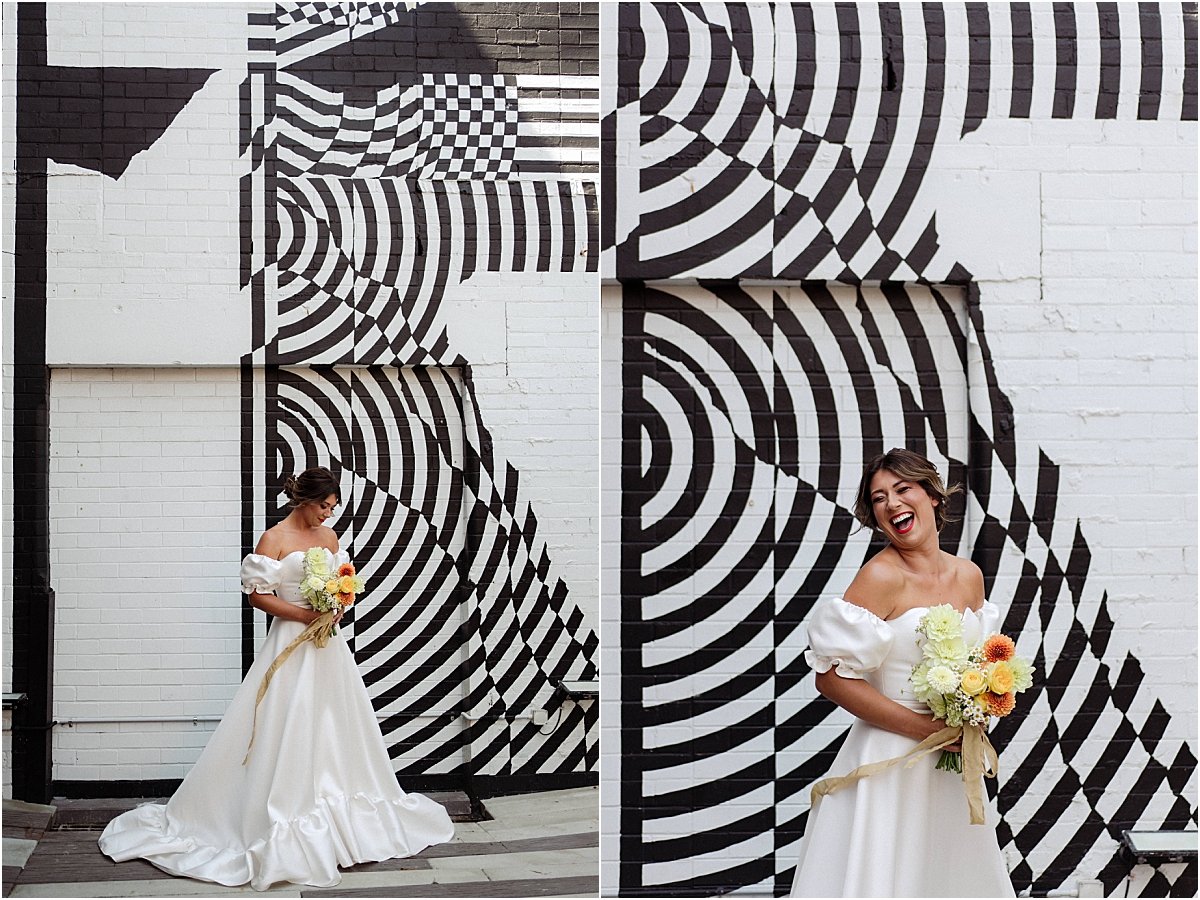 Bride standing in front of black and white mural at the Owens Collective in Islington, holding orange and yellow bouquet