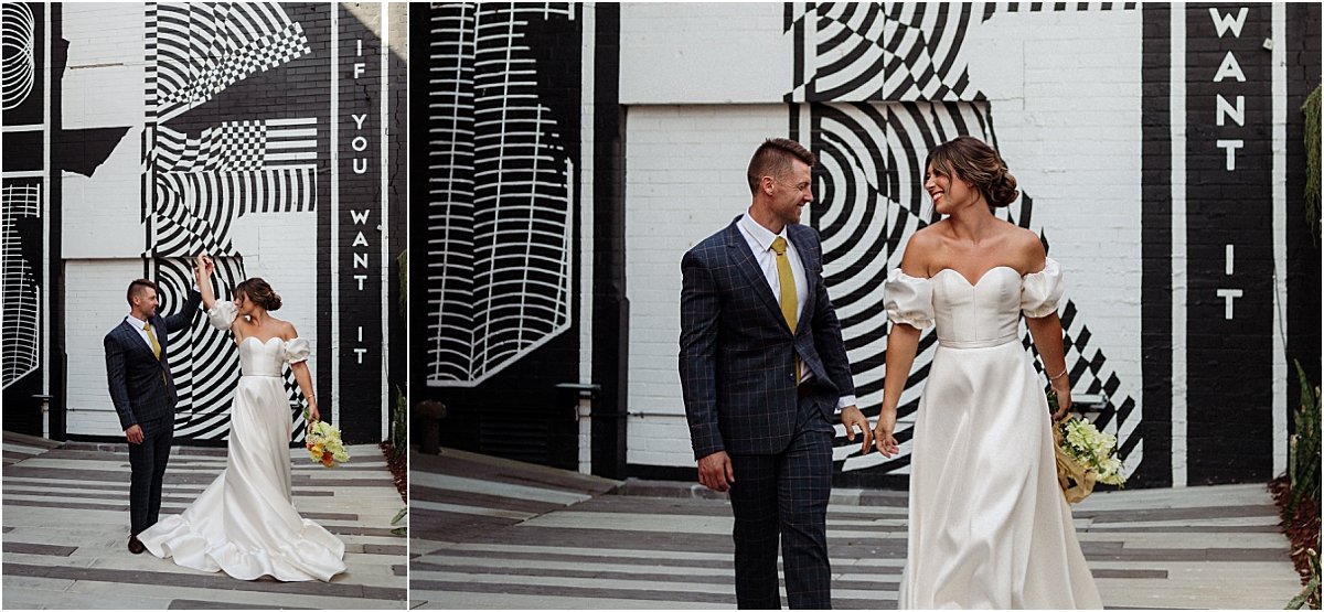Bride and groom walking and dancing in front of black and white mural in Newcastle NSW