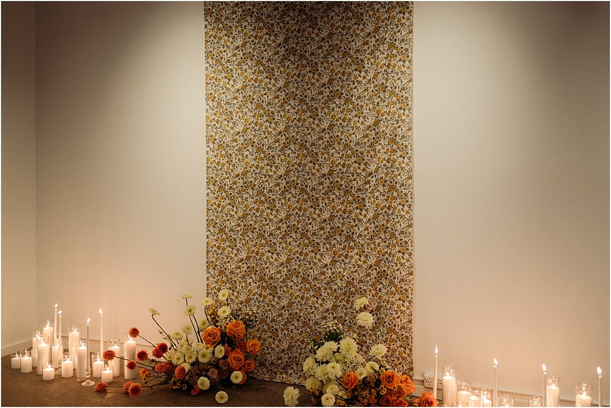 Mid-century modern style fabric hanging on white wall with candles and wedding flowers