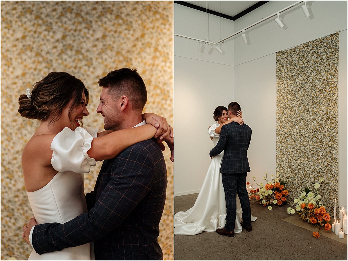 Bride and groom dancing together in front of retro fabric, pillar candles and orange and yellow floral nest