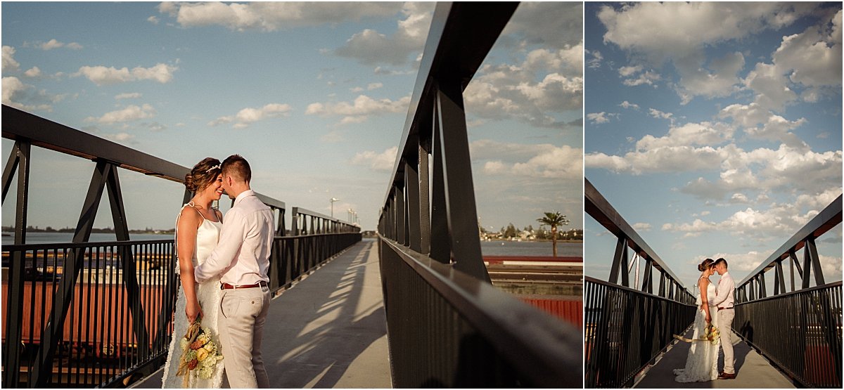 Bride and groom standing on bridge in Carrington NSW and leaning against each other