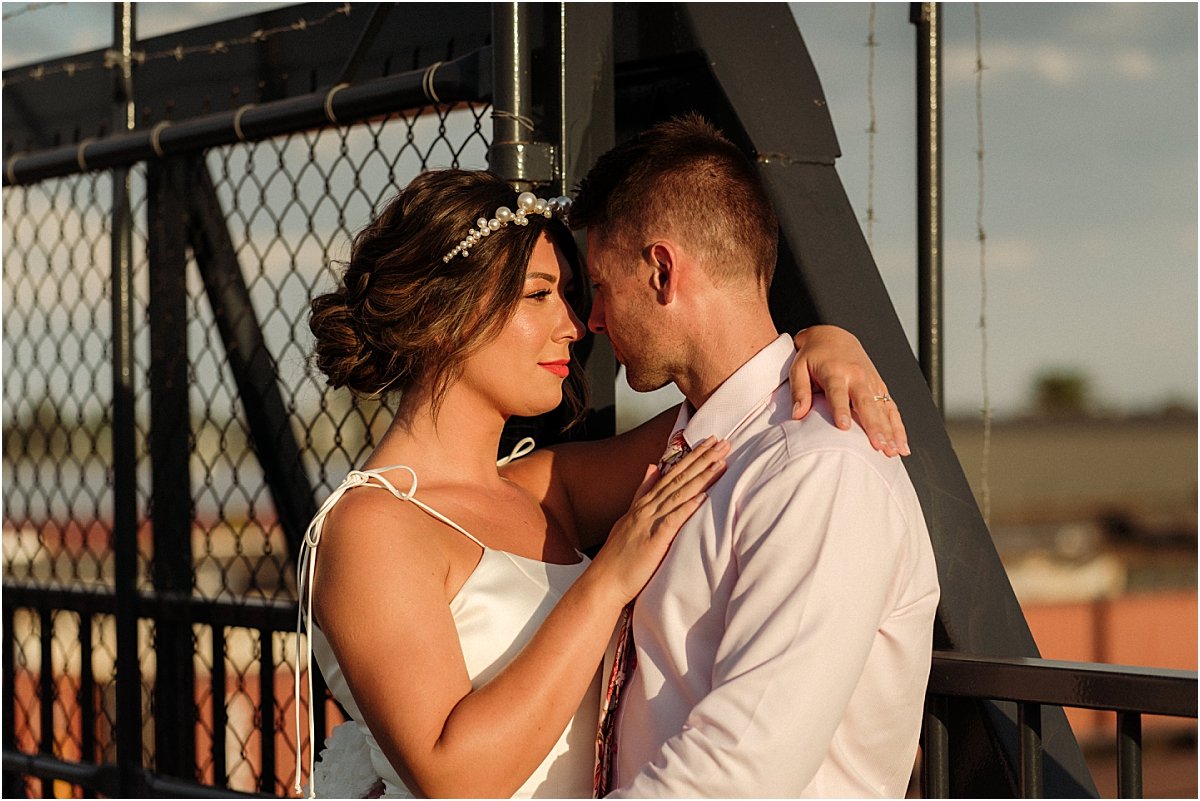 Bride and groom standing on bridge in Carrington NSW and leaning against each other