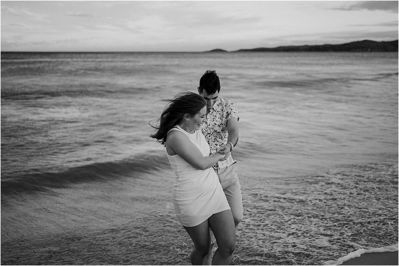 Couple walking and dancing together in the water at Box beach Port Stephens