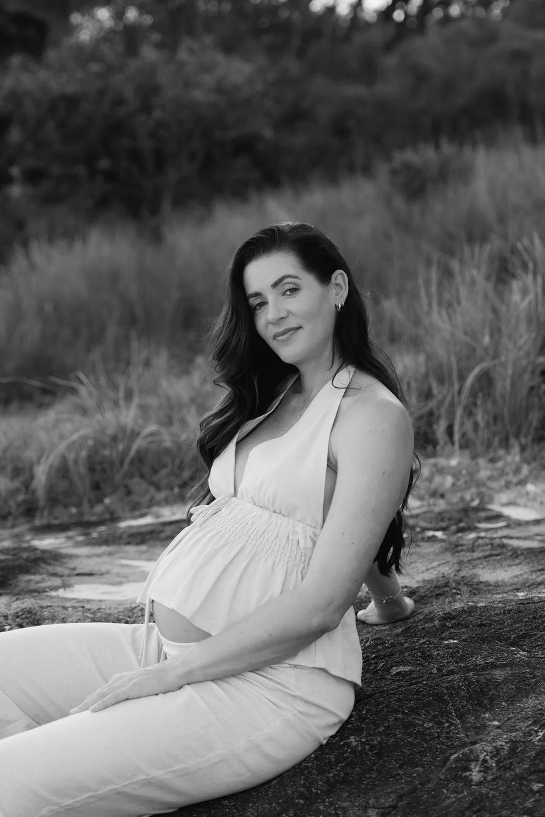 pregnant woman sitting and leaning on a rock, at Birubi Beach and Anna Bay