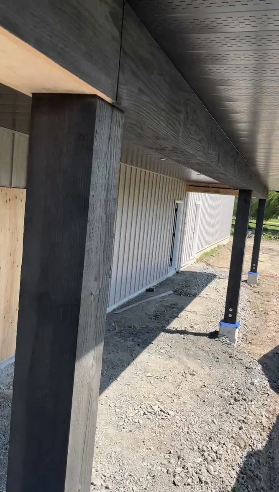 Construction site with vertical support posts, roofing structure, and exterior wall with vertical siding.