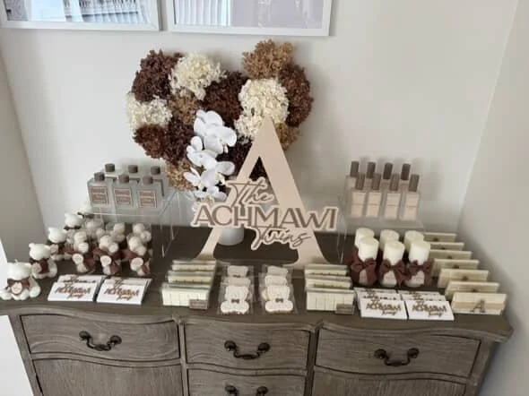 Decorative table with a floral arrangement, candles, and personalized signs for a celebration, possibly a birthday party.