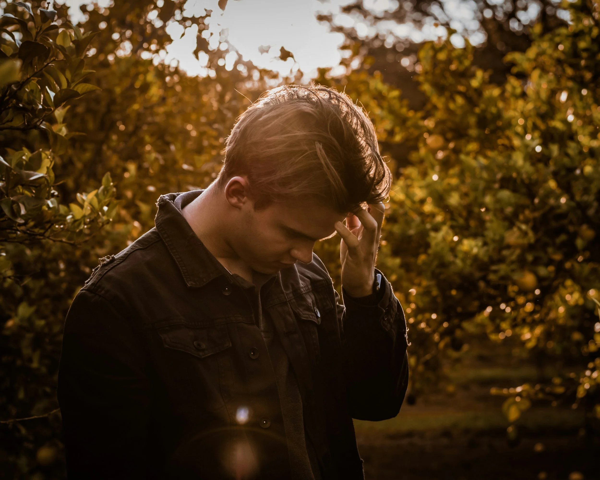 image of man holding head down around greenery expression of apprehensiveness in expressing emotions because of anxiety in relationships