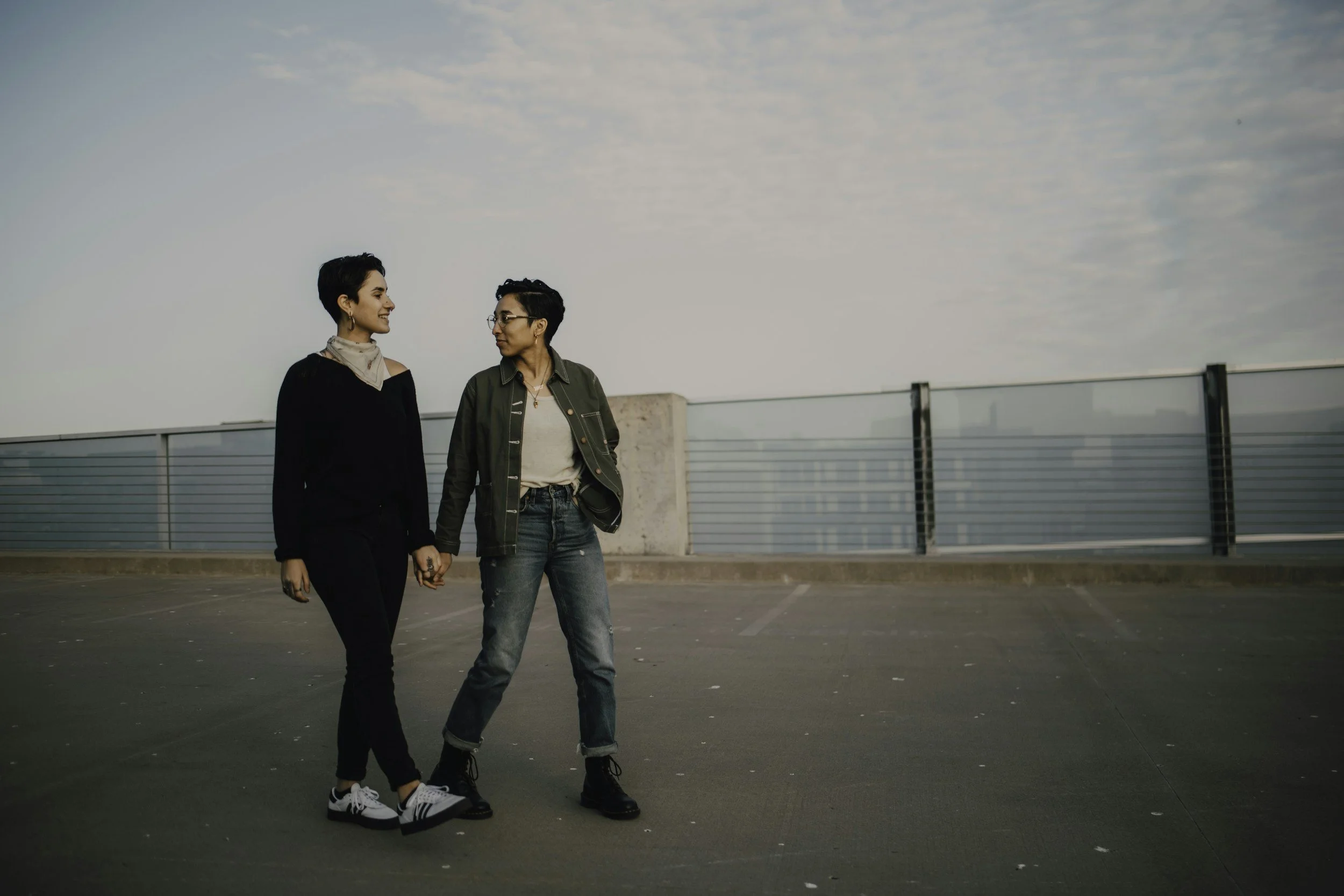 queer women or nobinary couple walking holding hands on concrete smiling with each other after online therapy in california for anxiety relief