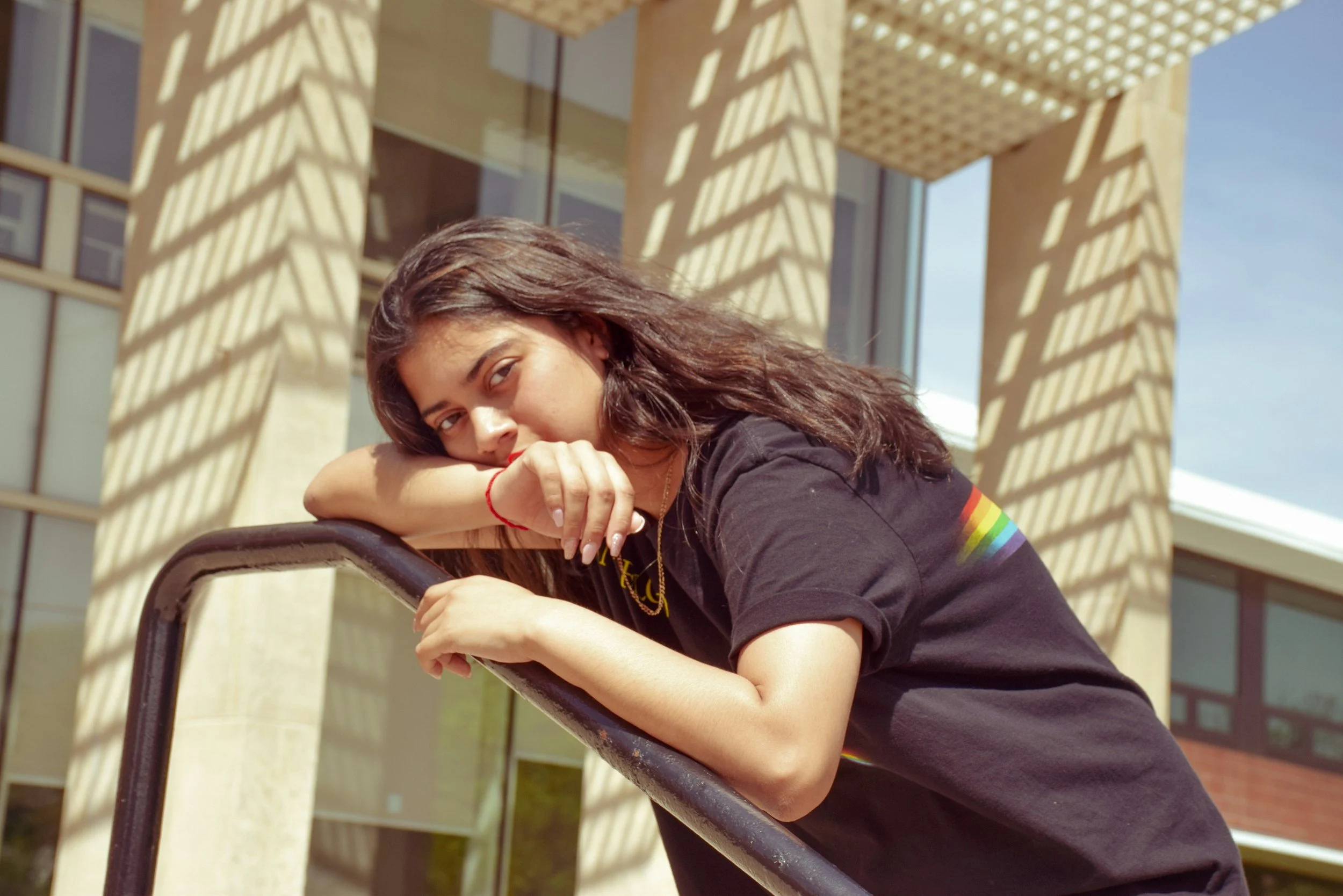 Queer BIPOC nonbinary adult close-up of hands resting on railing outside representing nervous system stress and anxiety