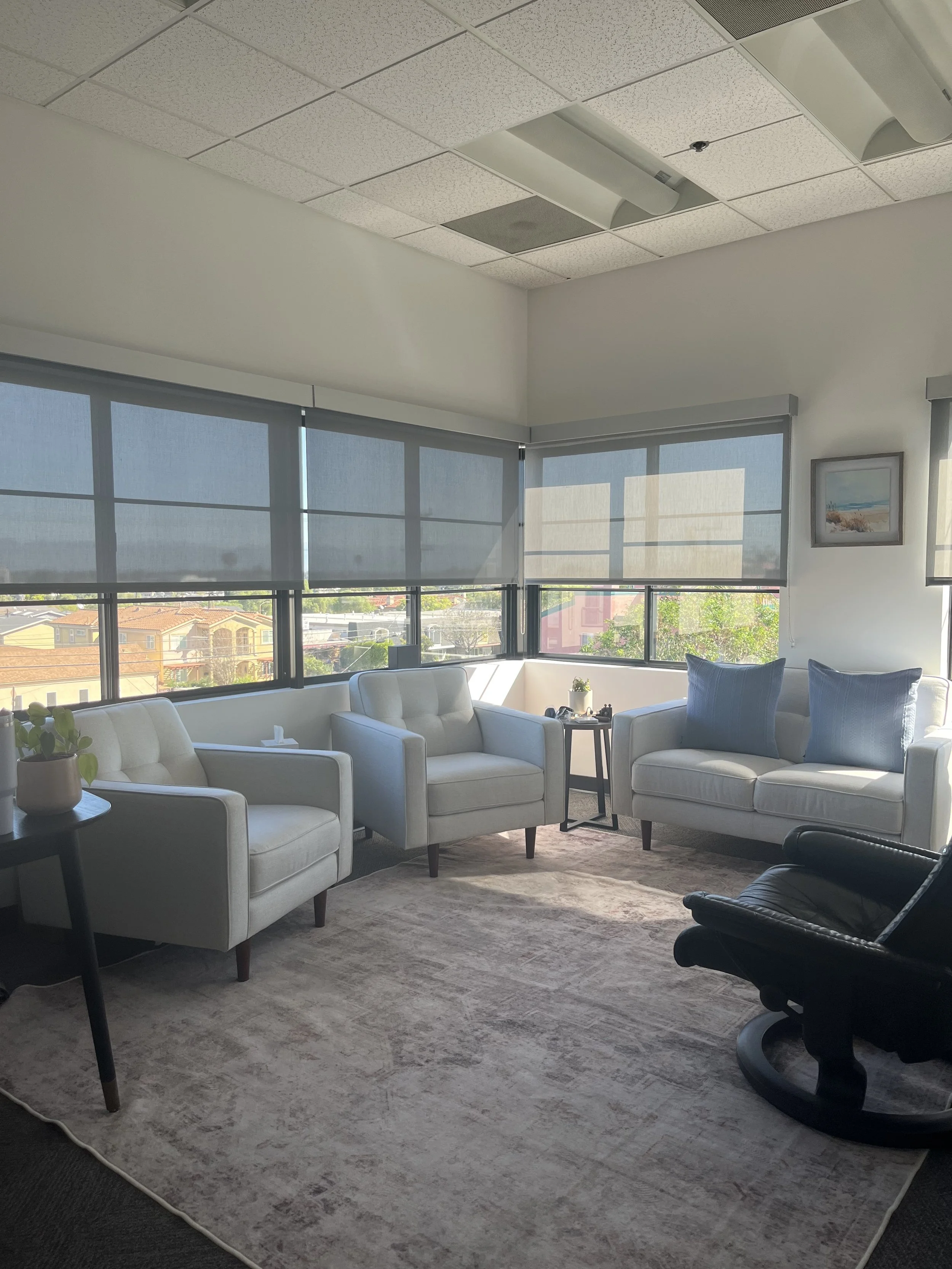 Image of cozy office space near beach cities with grey couches and sunlight coming in from big windows for therapy in torrance CA with an anxiety therapist