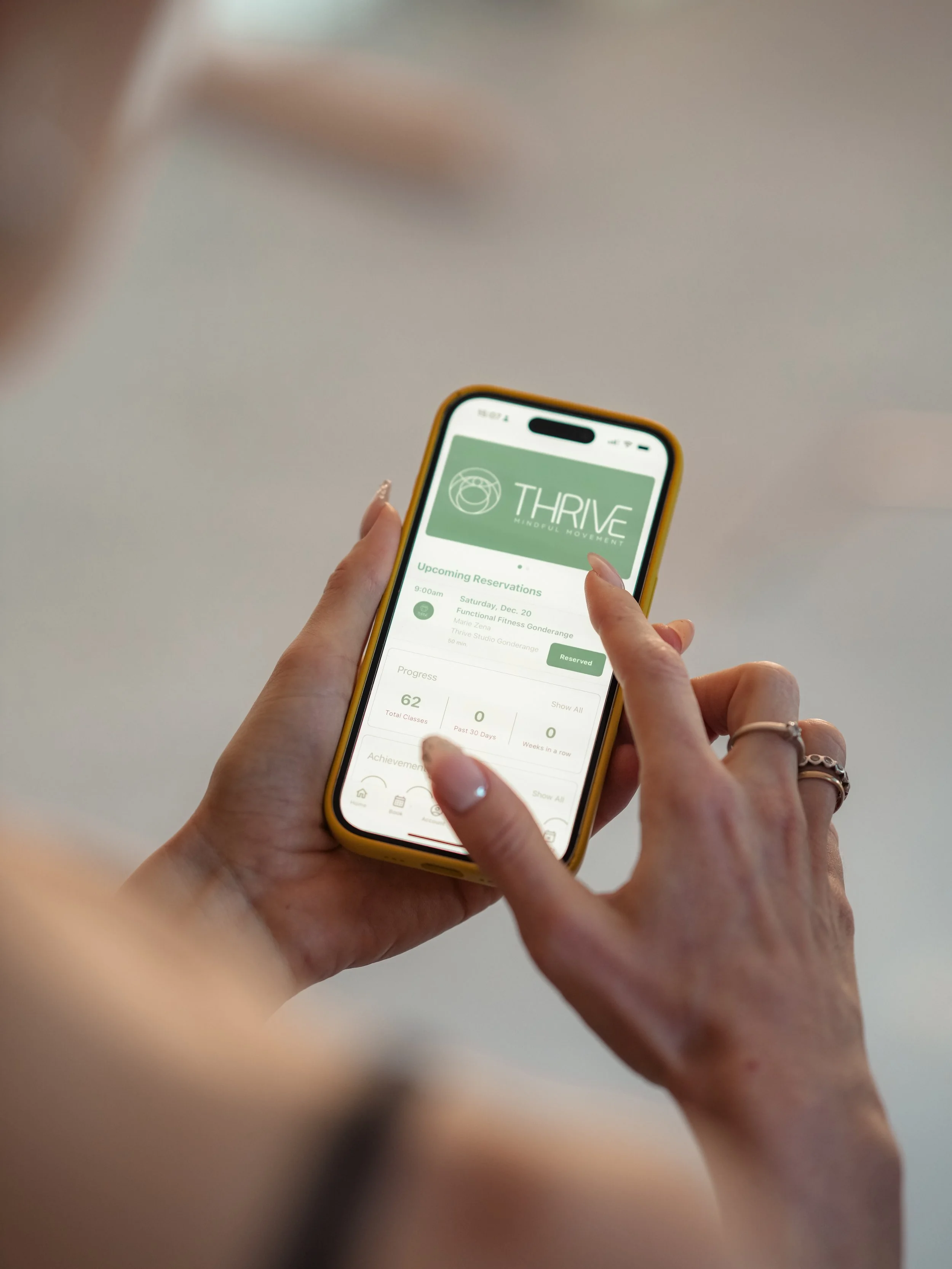 A person holding a smartphone displaying an app called Thrive, showing upcoming reservations and progress details.