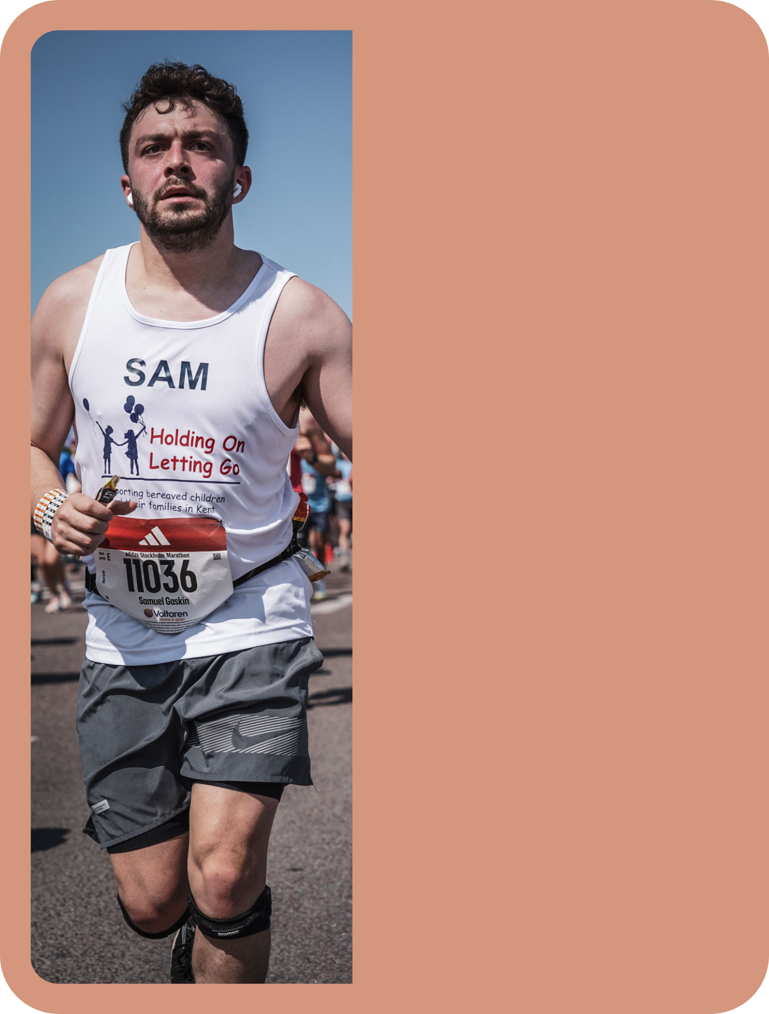 A man is running in a marathon, wearing a white sleeveless shirt with the name tag 'SAM' and printed text about supporting bereaved children. He is wearing gray athletic shorts, a wristwatch, and a race bib number 11036 with the name Samuel Gaskin. The background shows other runners and a clear blue sky.