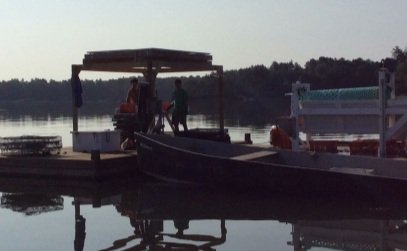 People on a dock near a boat on a calm lake during the daytime.