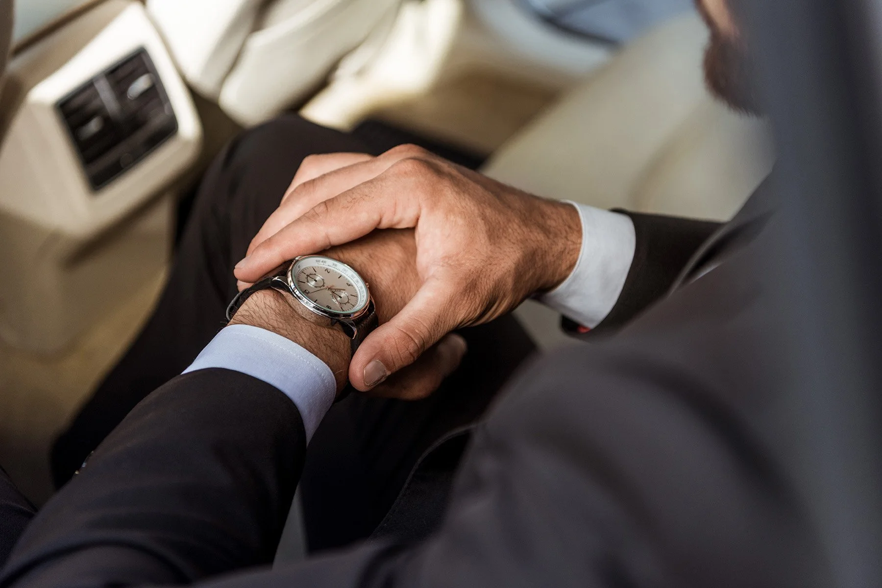 Man in a car looking at his luxury mechanical watch on his wrist