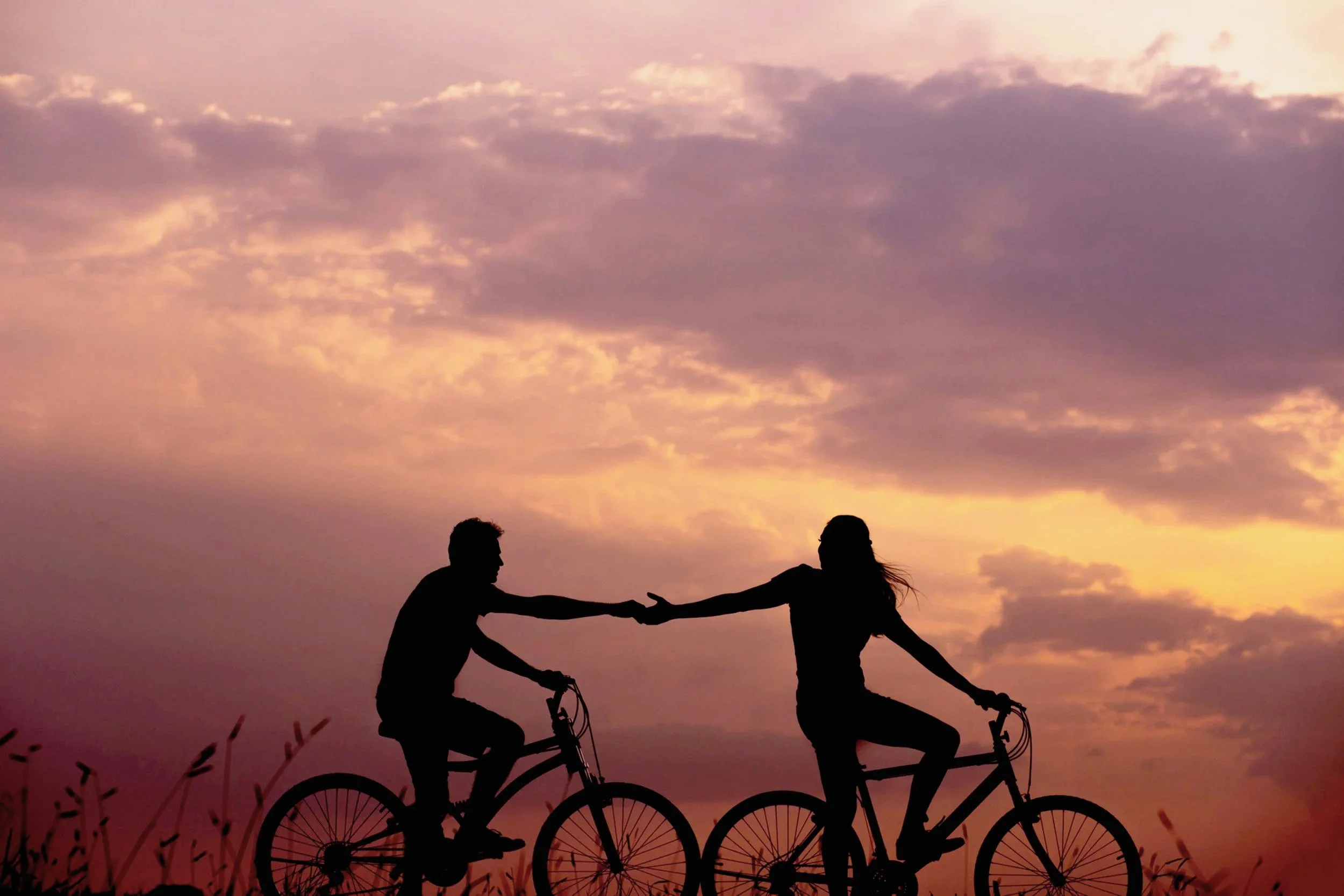 Two bicycles silhouetted against a colorful sunset.