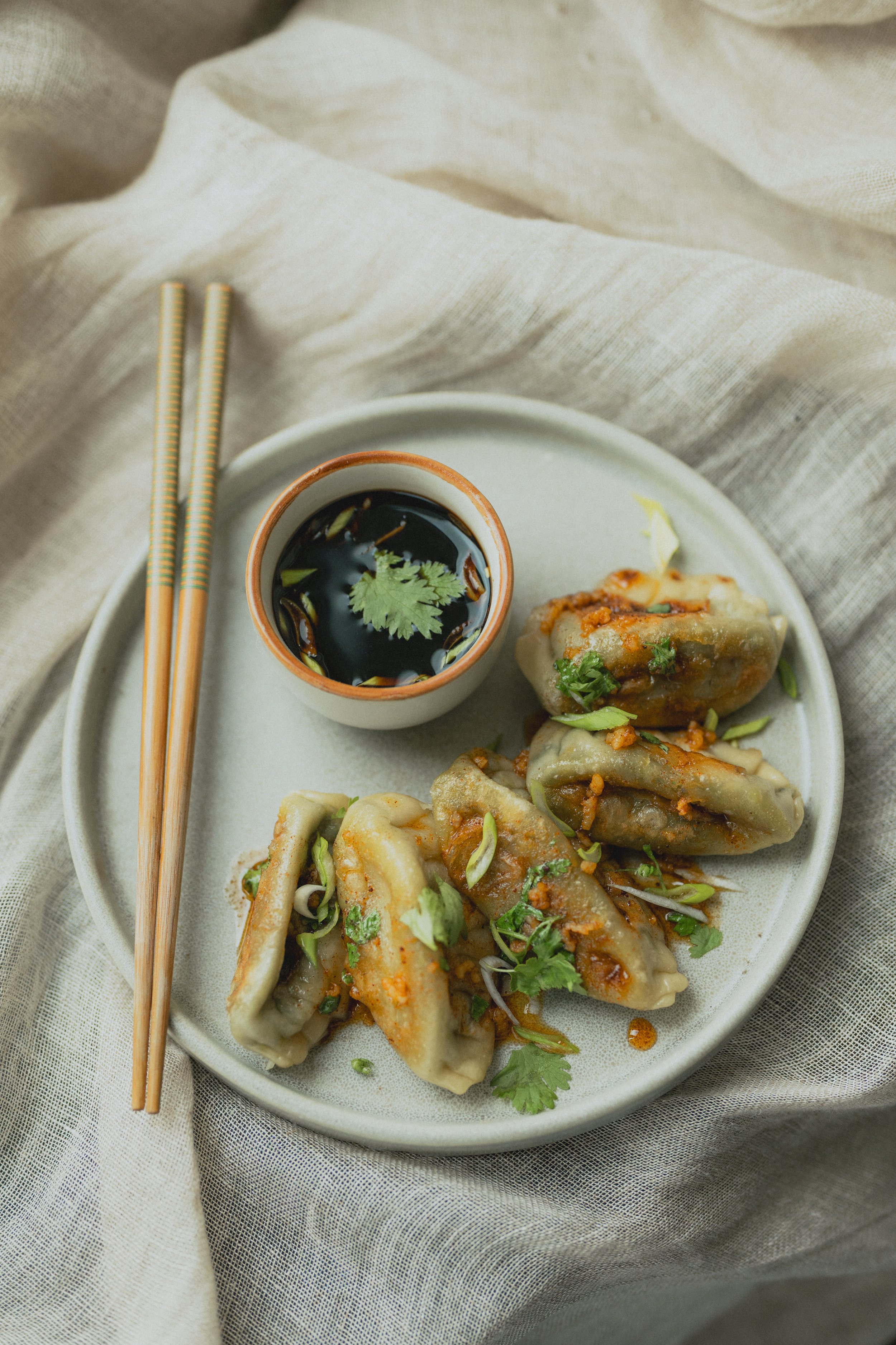 Photographie culinaire de gyozas dorés pour Edonia, assiette stylisée et lumière naturelle