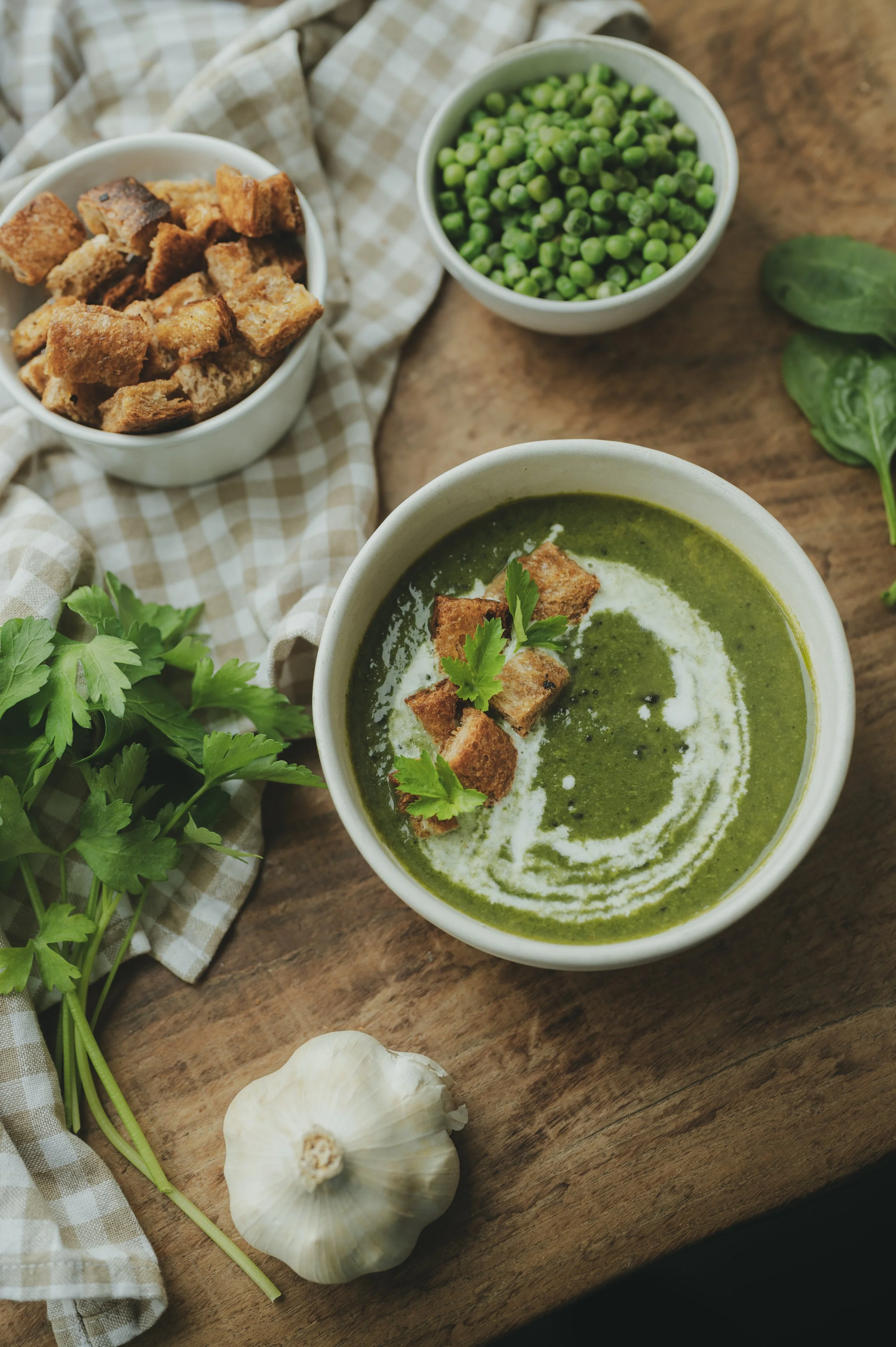 Photo culinaire éditoriale d’une soupe aux légumes verts avec croûtons et herbes, ambiance rustique