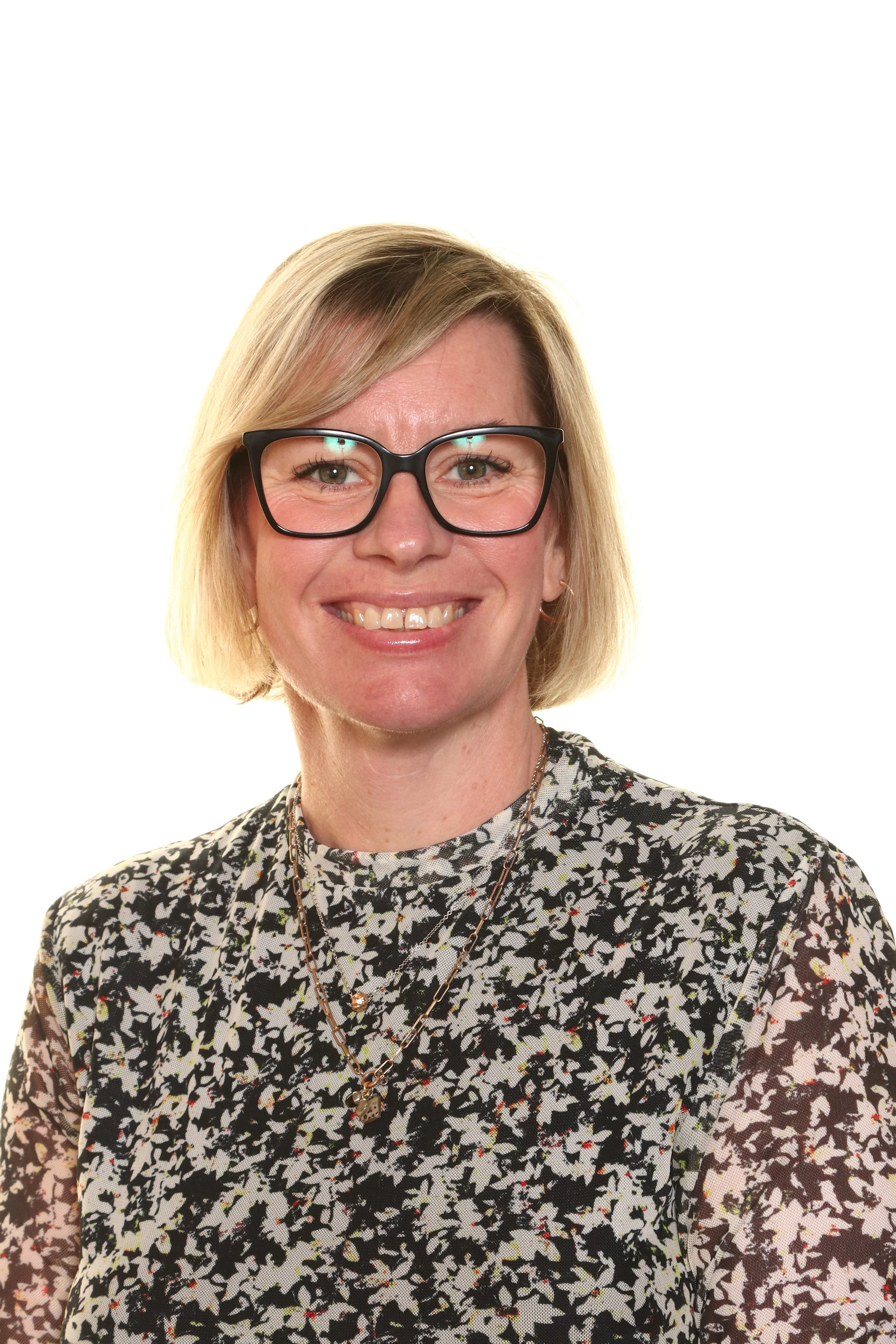 Headshot of a man with dark hair, wearing a striped dress shirt, dark tie, and a blue lanyard against a plain white background.