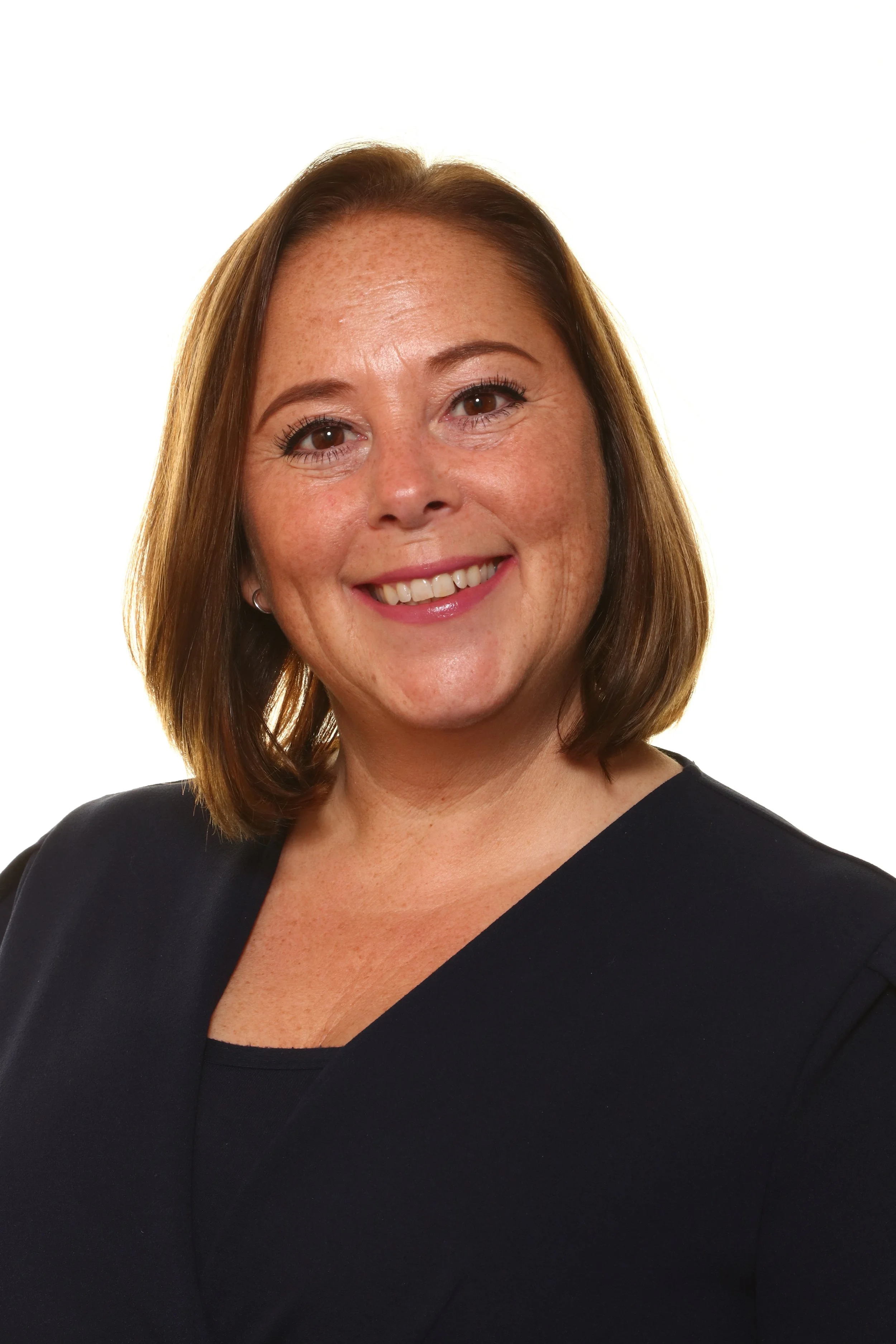 Close-up of a middle-aged man with gray hair, wearing a checkered shirt, against a plain white wall.