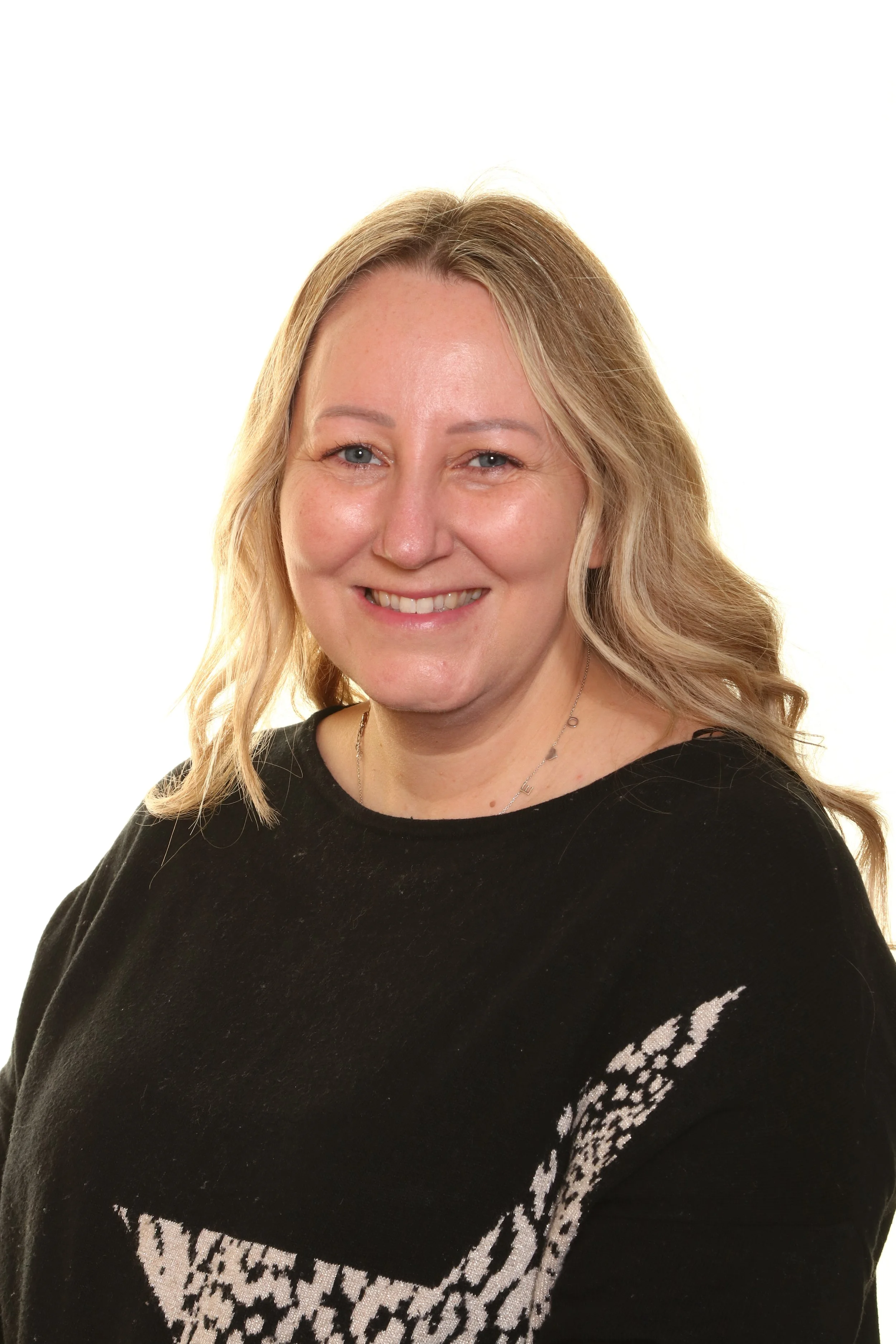 Professional man in a dark suit with a white shirt and striped tie, posing against a light background.