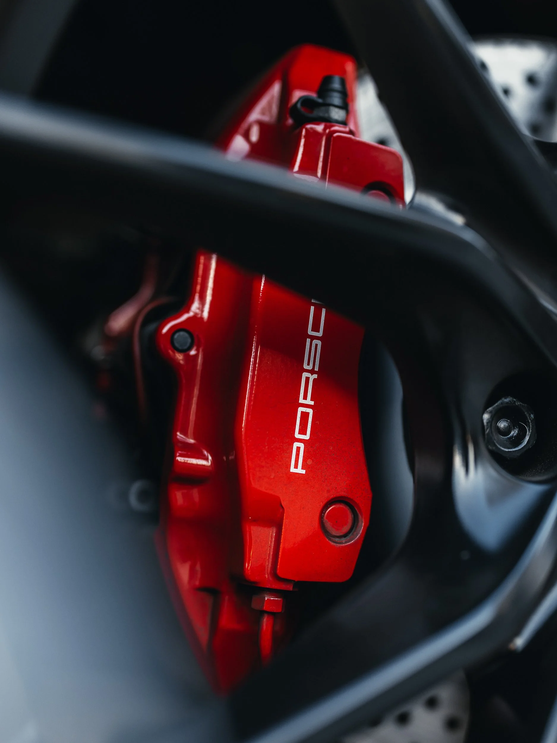 Close-up of a red Porsche brake caliper, photographed by Rob Ash