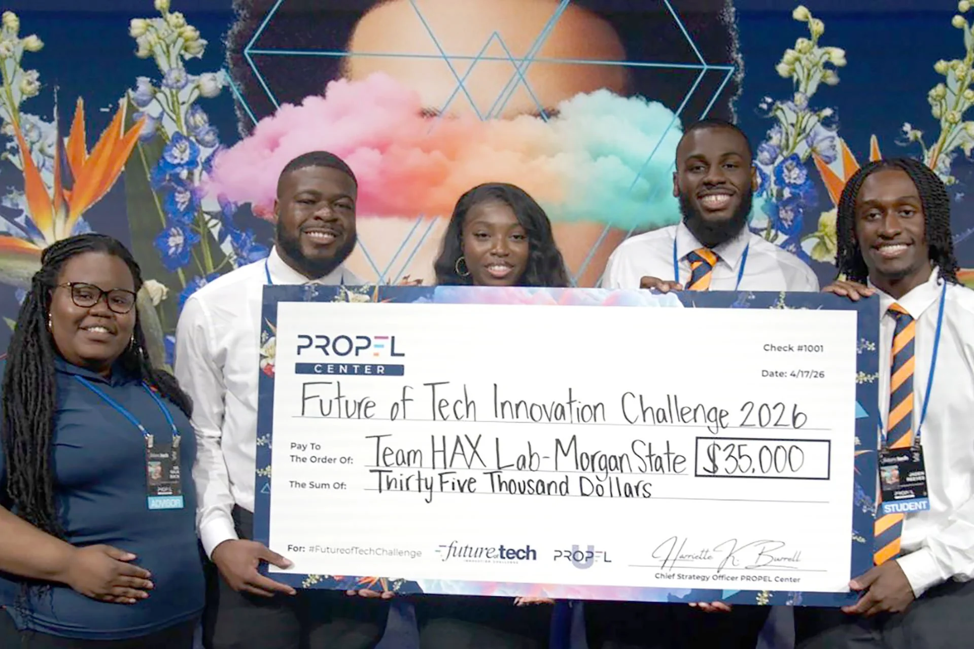 four students hold a giant $35K check standing with their advisor Naja Mack