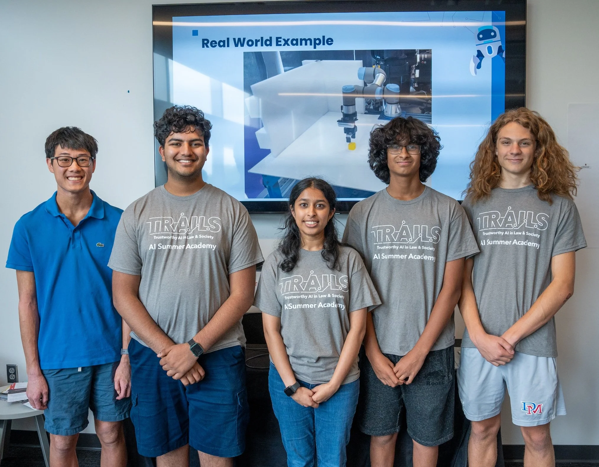 five campers wearing TRAILS t-shirts in front of their presentation that says "real world example"
