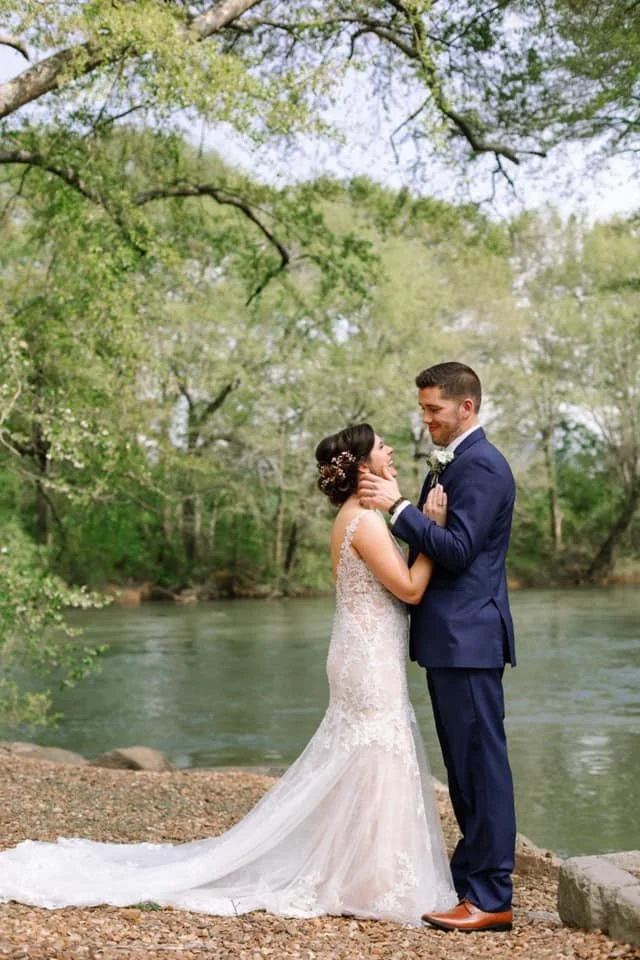 Bride and groom posing looking at each other by a pond outside