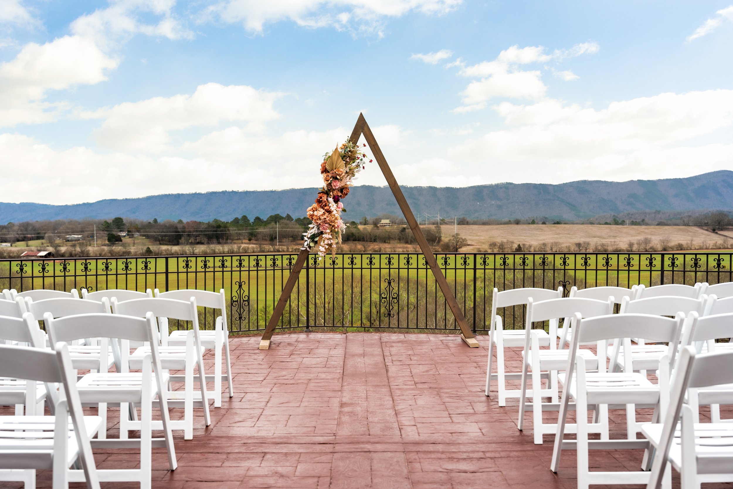 White resin chairs and simple wooden arbor with floral arrangement overlooking Eastern Tennessee mountains.