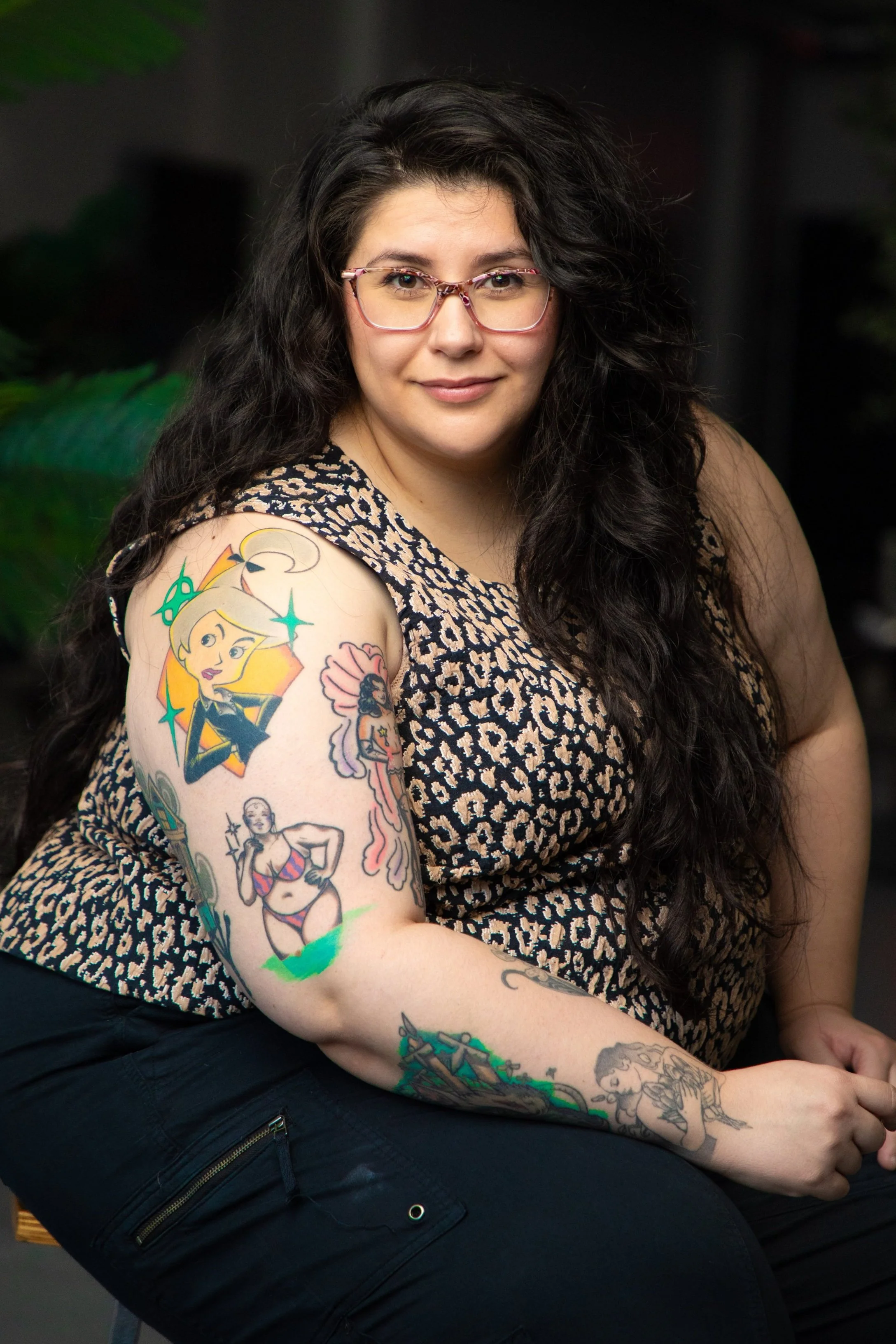 Headshot of therapist Libby Ebert. She is smiling at camera with glasses on and tattoos on her arm.