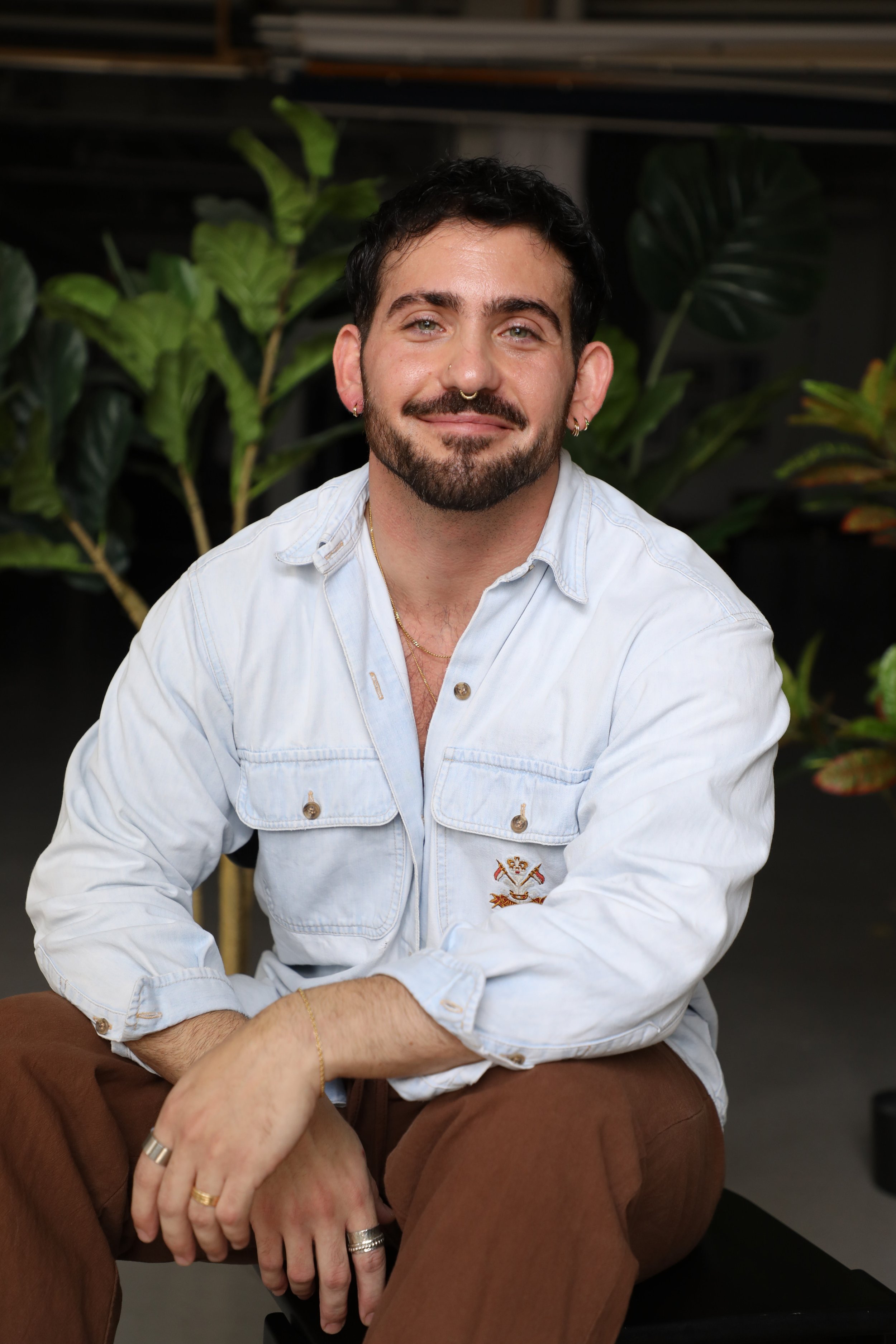 J Blu therapist smiling at camera wearing white button down shirt and brown pants