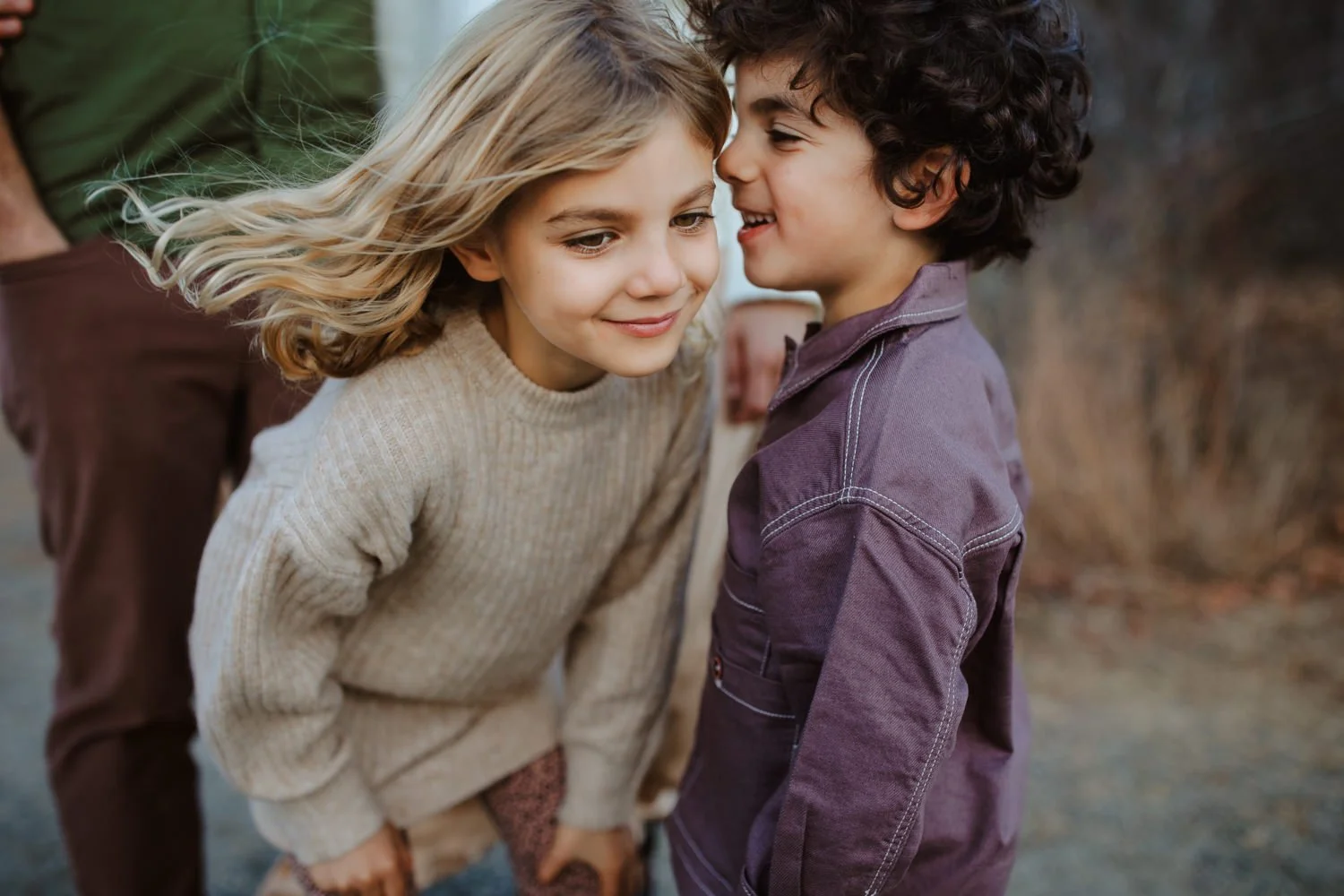 Two young children smiling with foreheads nearly touching during an outdoor portrait session
