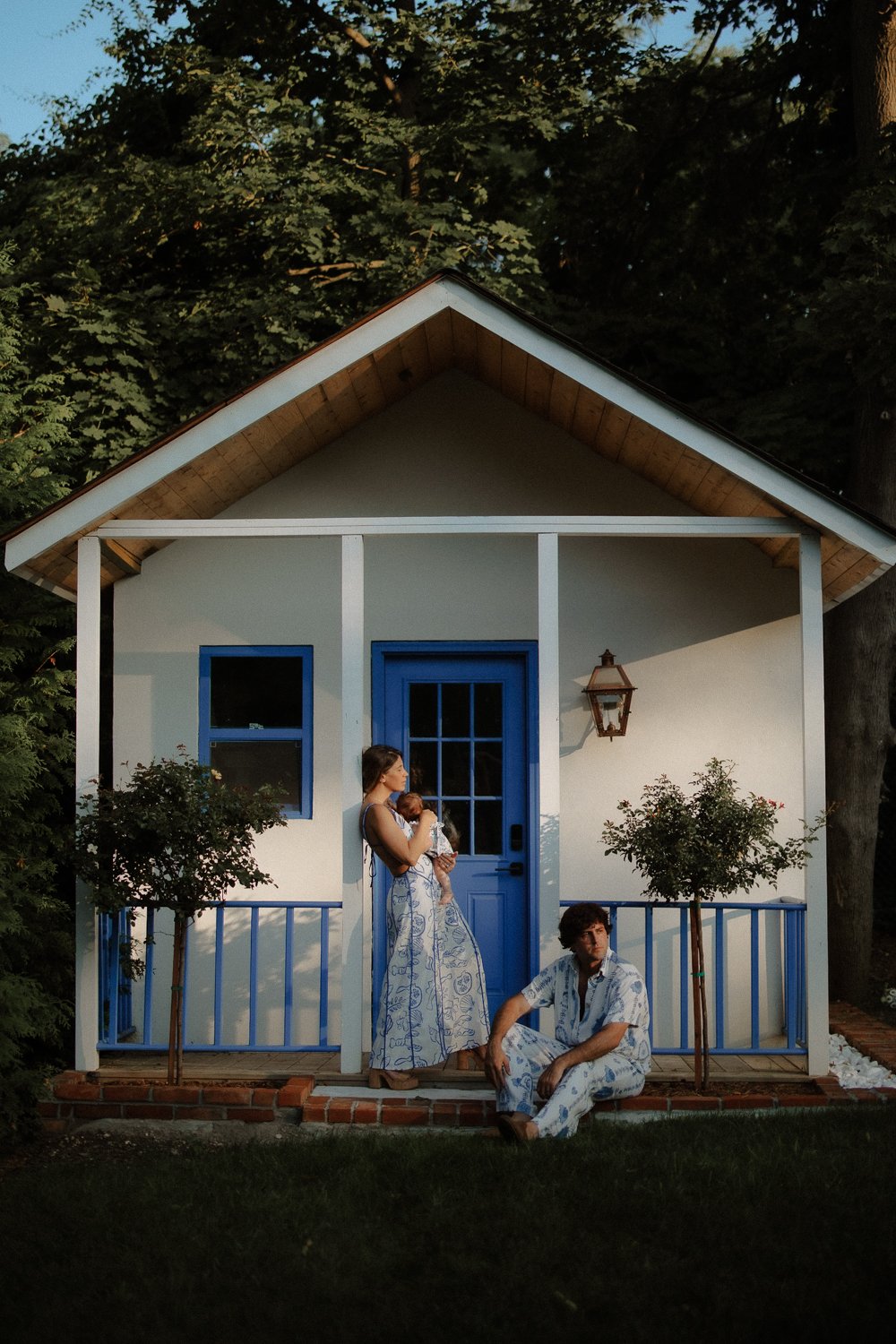 Family of three in matching blue print outfits on a cottage porch, New York family photography session