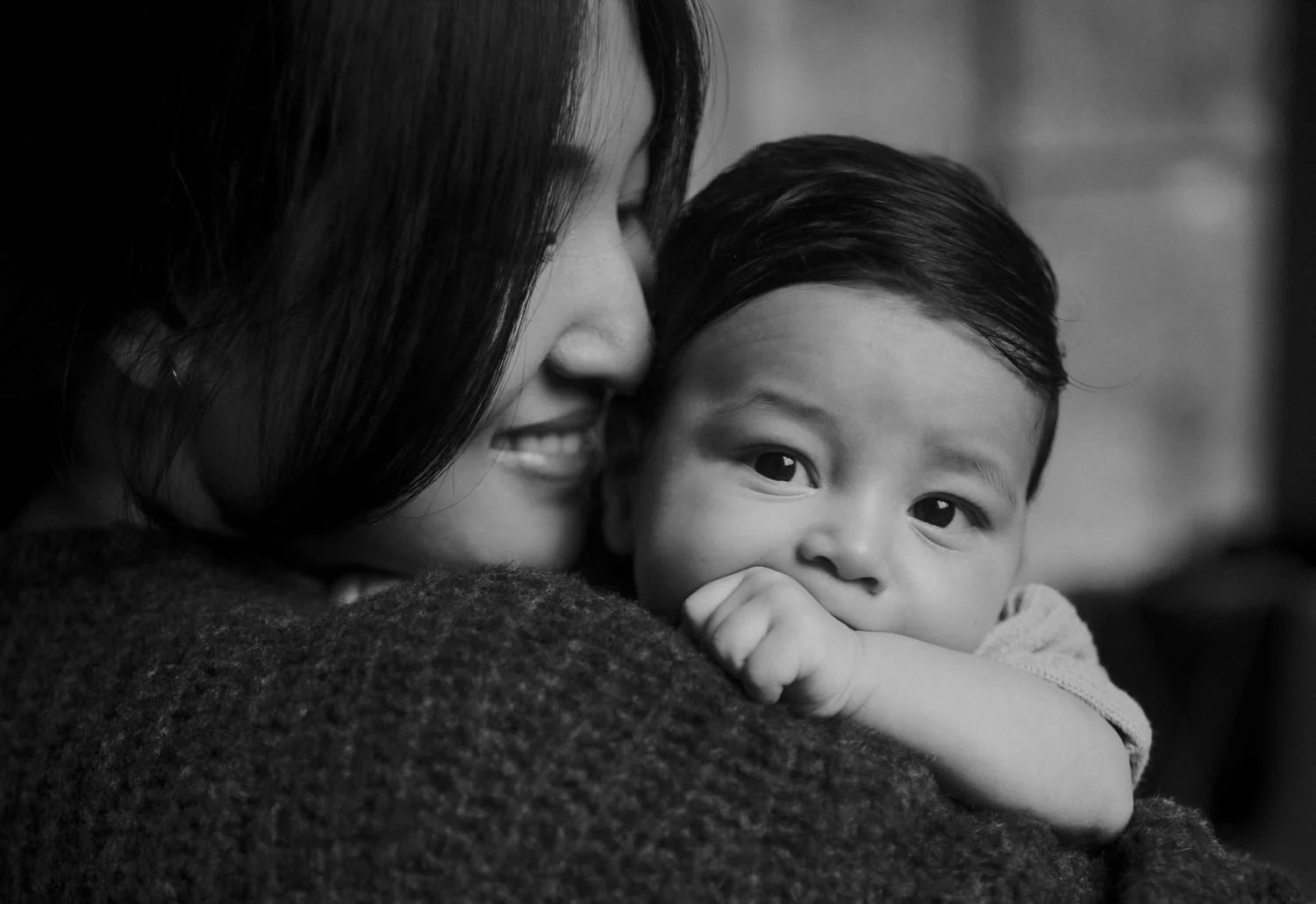 Black and white close-up of a mother nuzzling her smiling baby, newborn photographer in New York