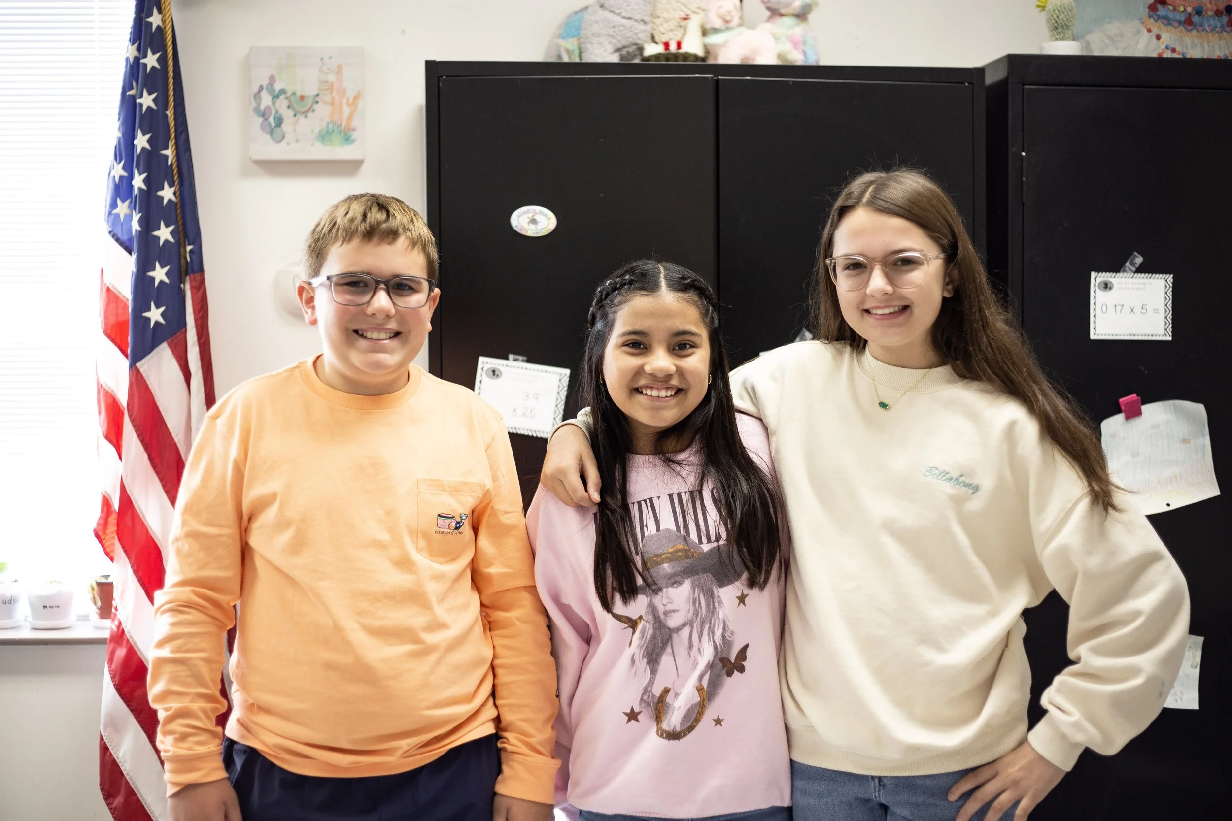 Group of smiling children posing in front of a colorful geometric wall.