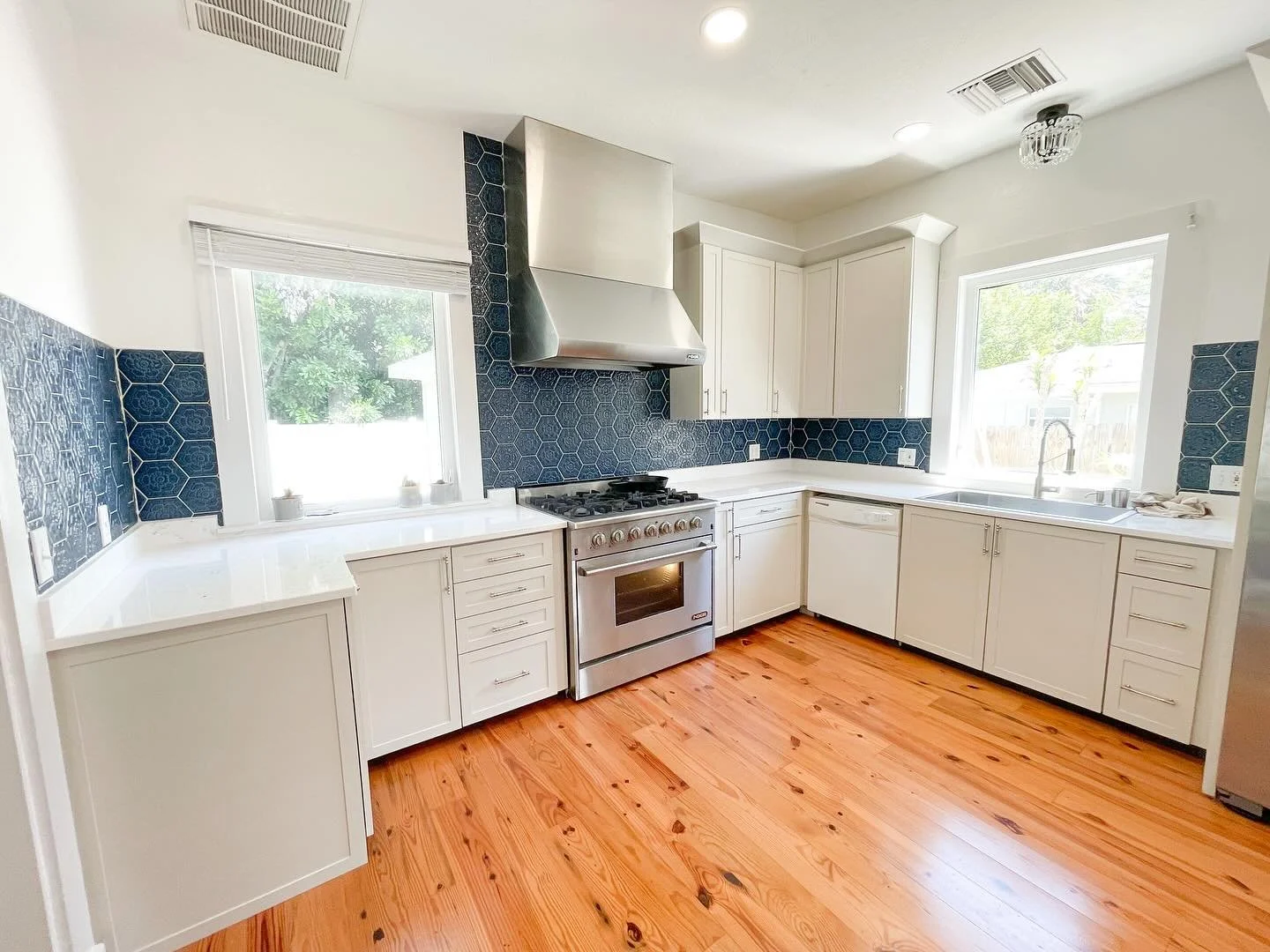 Bright, clean, and anything but ordinary ✨ 
This kitchen features a crisp white palette, warm hardwood floors, and a bold blue hex tile backsplash that brings just the right amount of contrast. Our client wanted a unique pattern, and we loved bringi