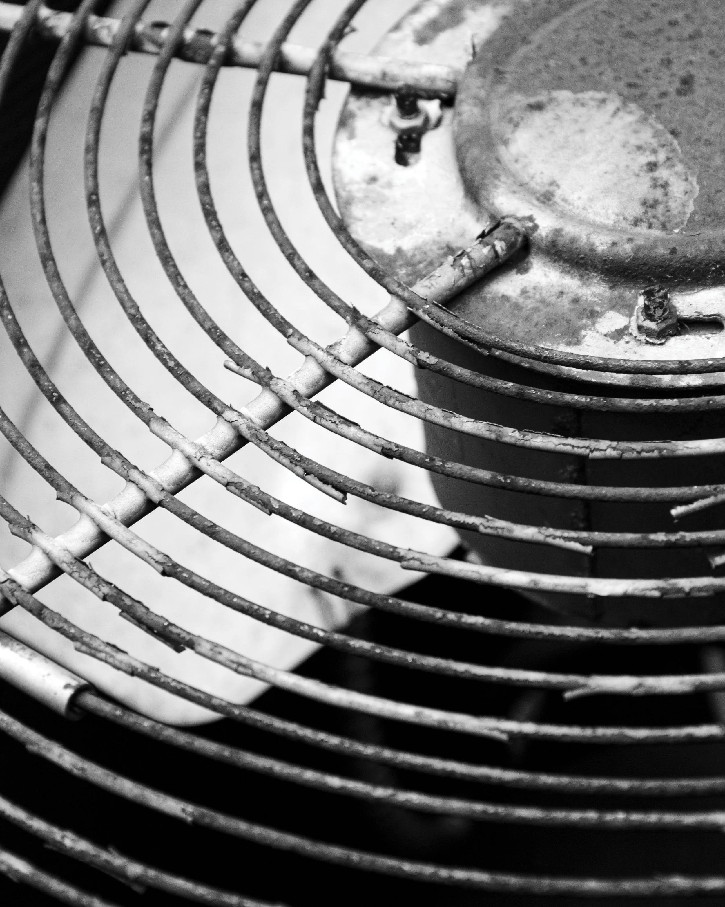 Close-up of an old, rusty metal fan with concentric circular blades and protective grill.