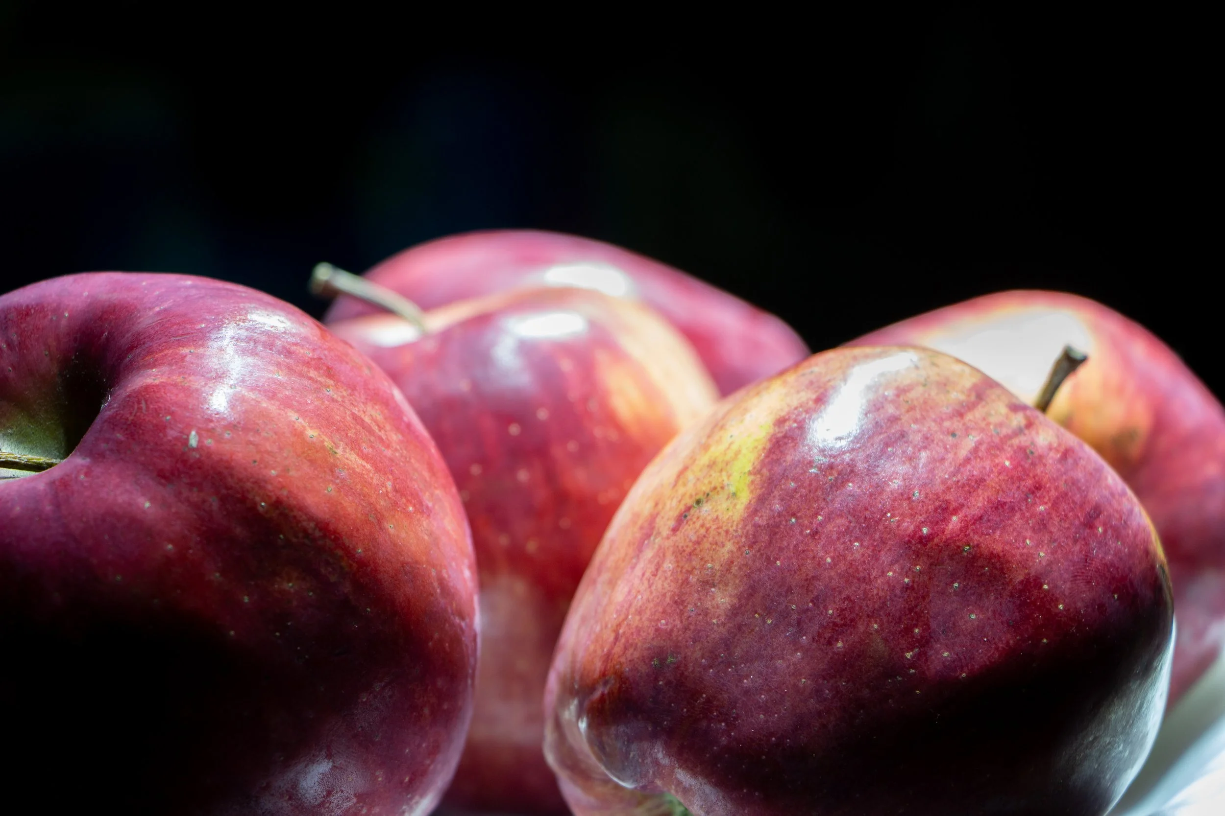 Close-up of several fresh red apples against a dark background.