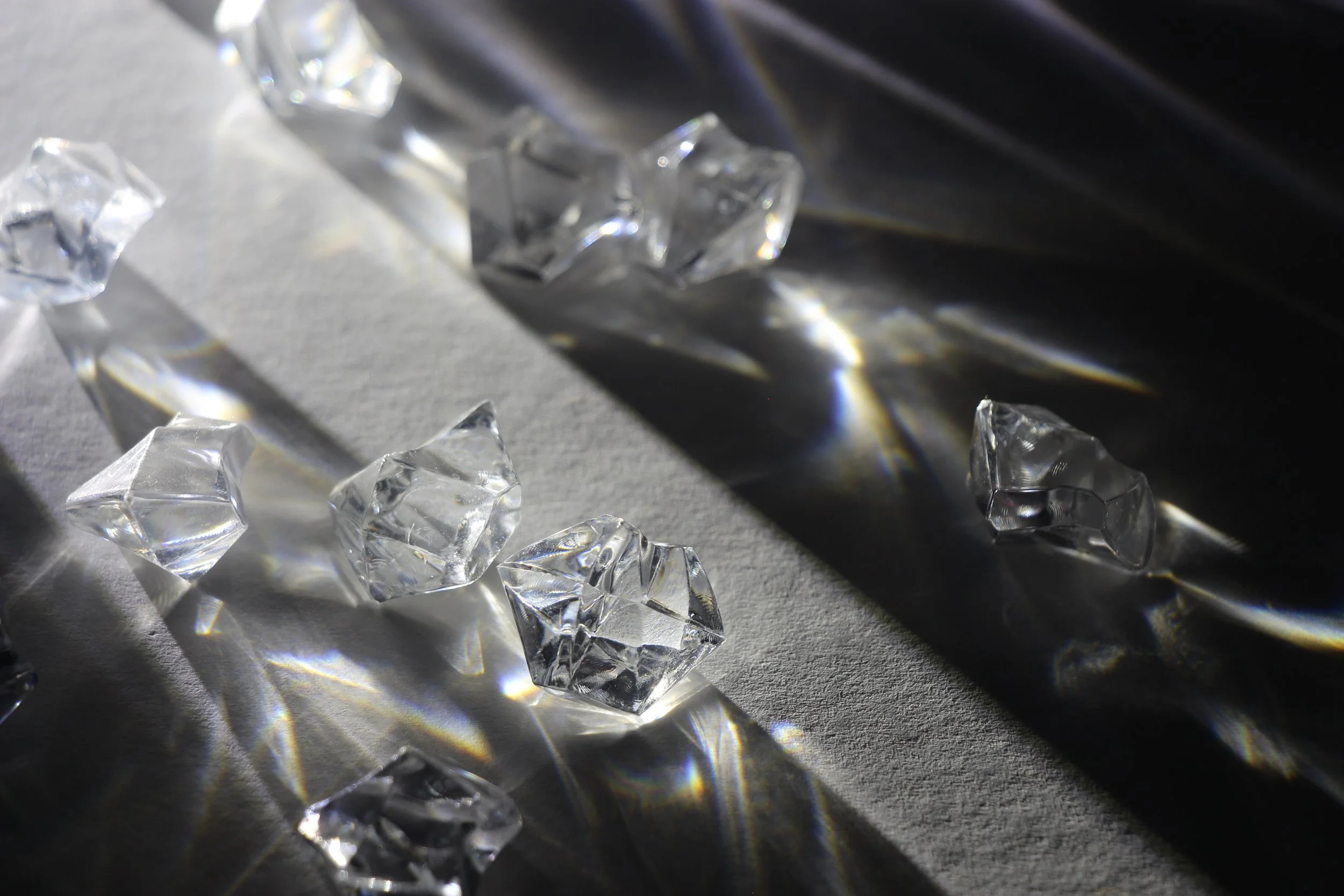 Clear glass ice cubes and a shiny metallic surface with reflections and shadows.