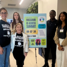 Four young women standing next to a poster at the Missouri Access Summit, which is scheduled for September 7, 2024, with a blue and white color scheme.