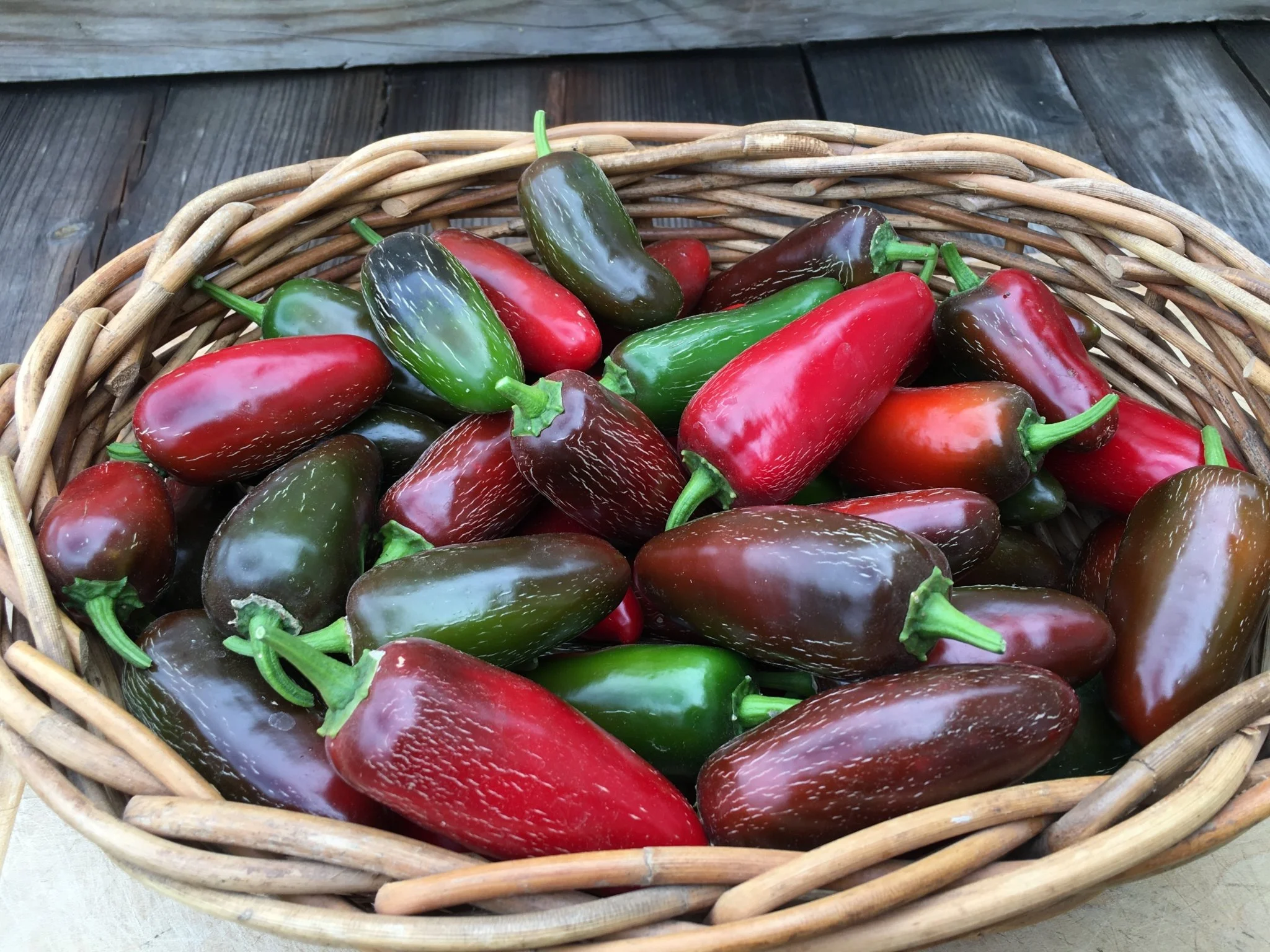 red and green jalapeno peppers in a basket