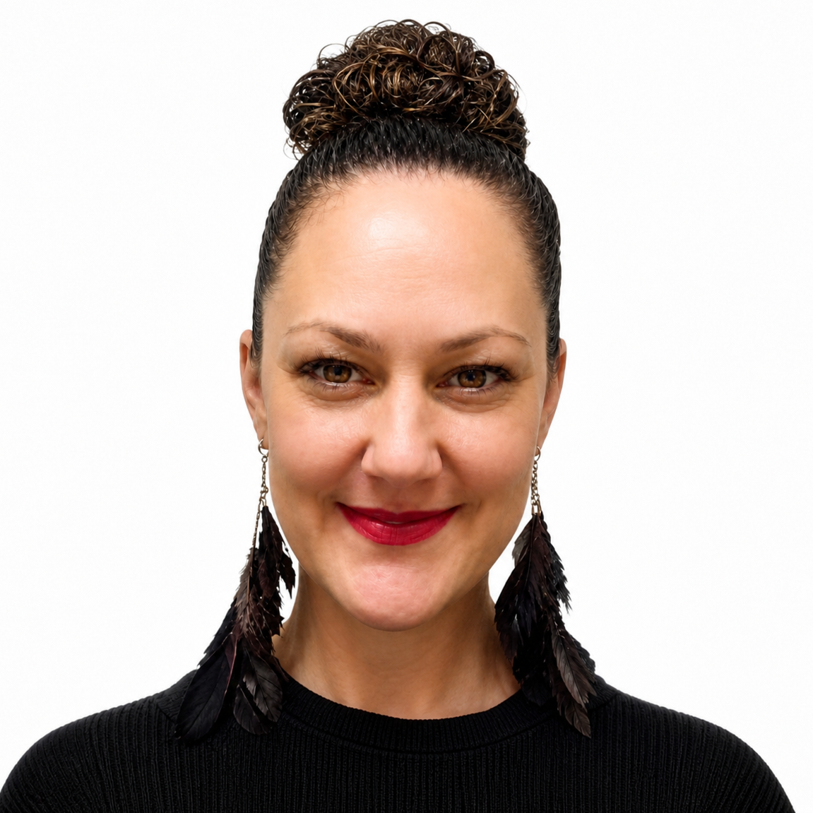 Close-up of a woman with dark hair tied back, wearing earrings, and smiling at the camera.